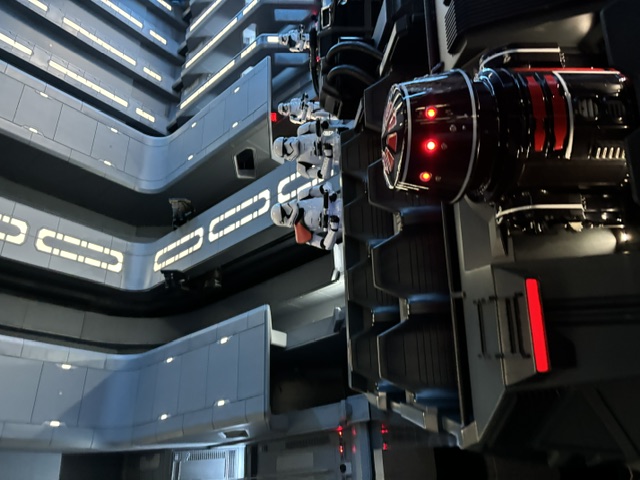 Interior view of a Star Wars spacecraft with stormtroopers lined up along a corridor with blue neon lighting and control panels