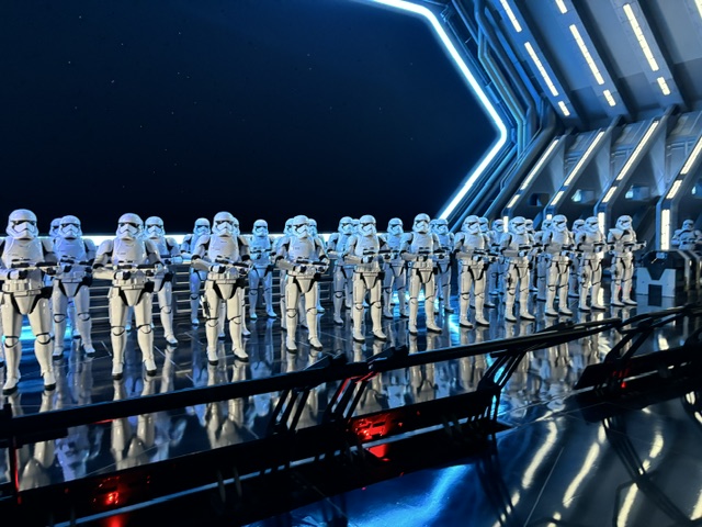 Multiple stormtrooper figures standing in formation inside a futuristic spacecraft interior with angular metallic walls and blue lighting