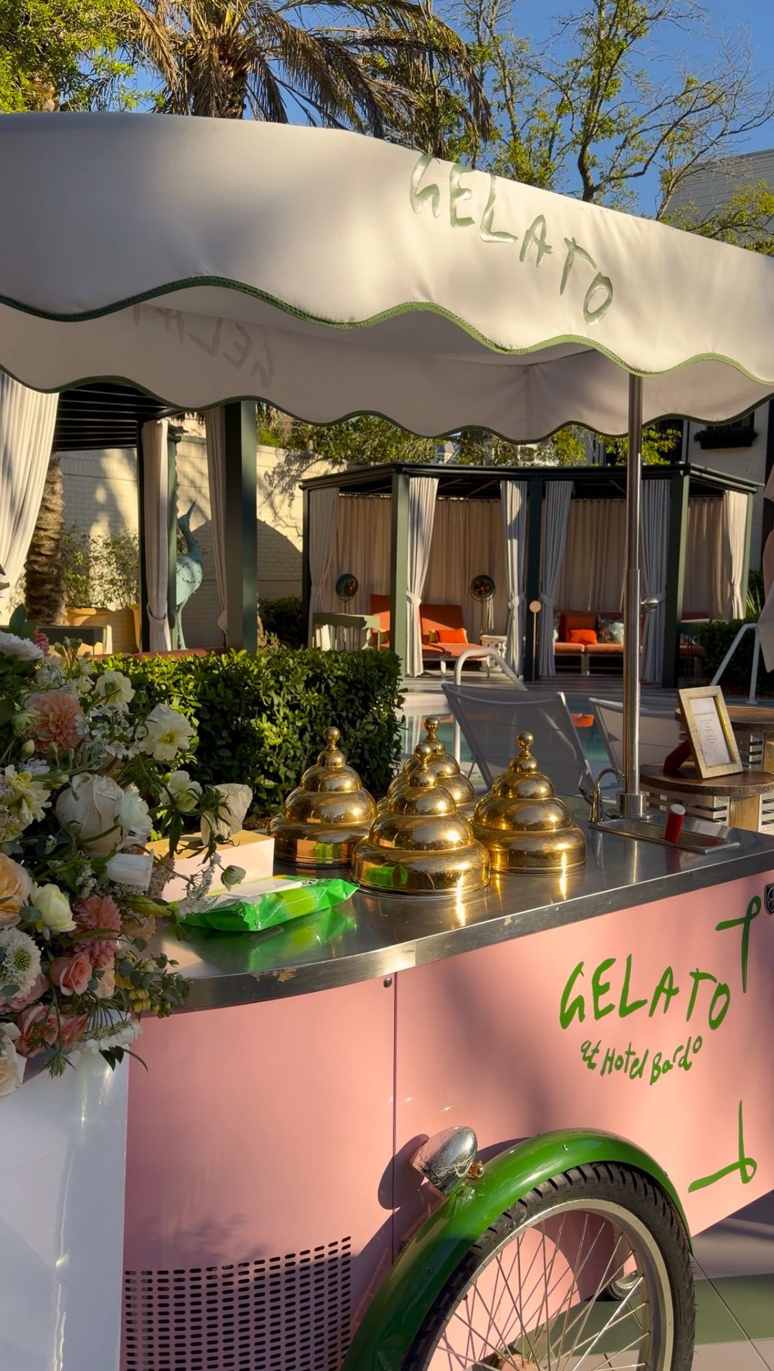 Pink gelato cart with green accents and brass serving domes at an outdoor venue