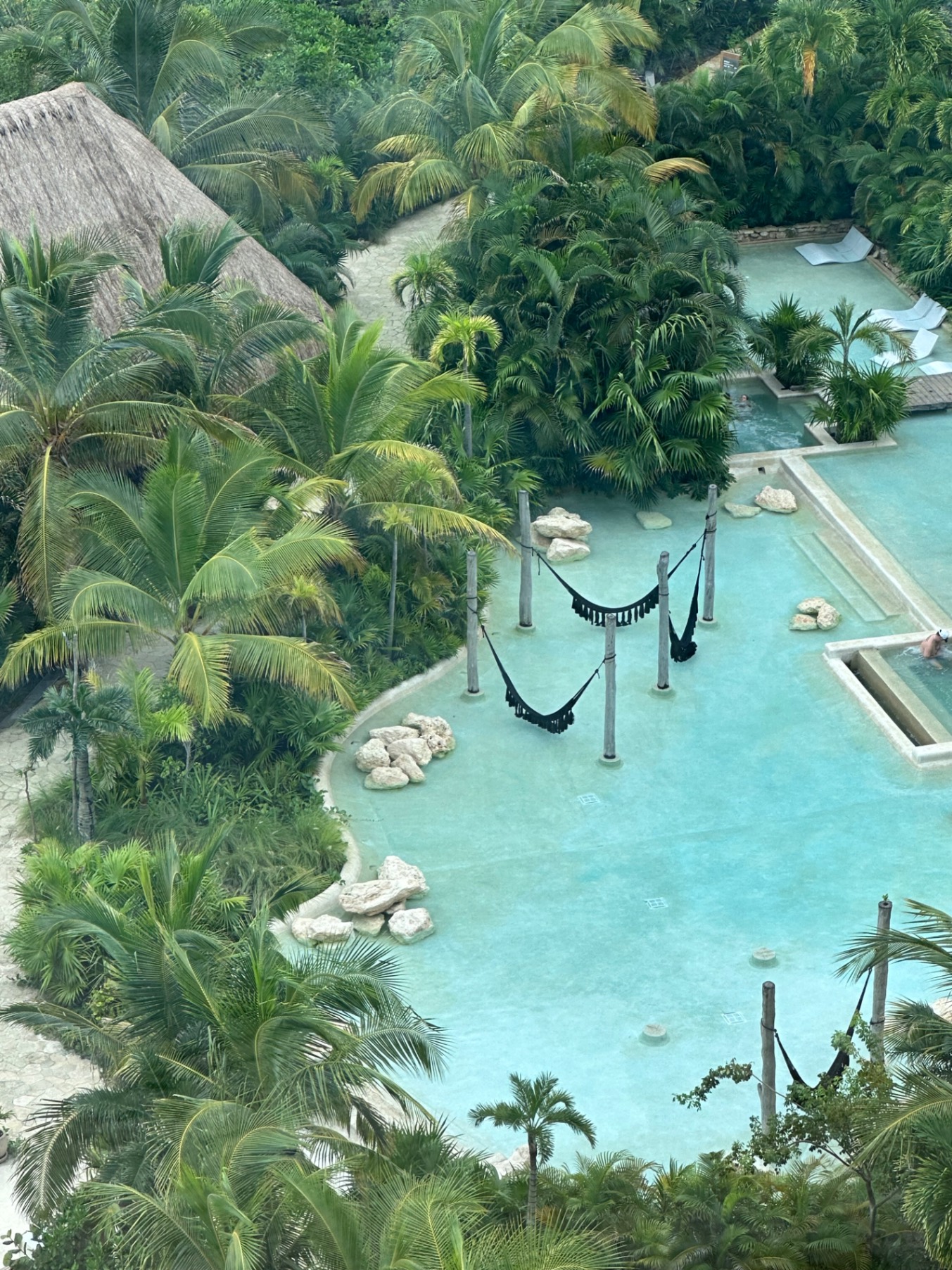 Aerial view of turquoise lagoon with black hammocks, limestone rocks, thatched structures, and palm trees
