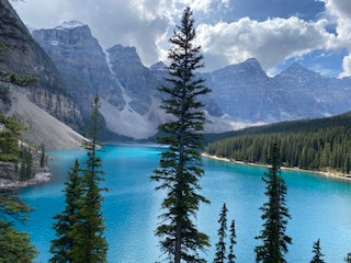 Turquoise alpine lake surrounded by dense coniferous forest and steep rocky mountain peaks