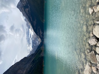 Crystal-clear turquoise lake nestled between tall rocky mountain cliffs with forested slopes