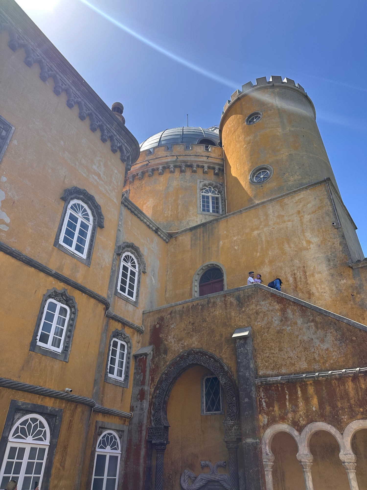 Weathered yellow stone tower with domed roof and ornate windows in Sintra, Portugal