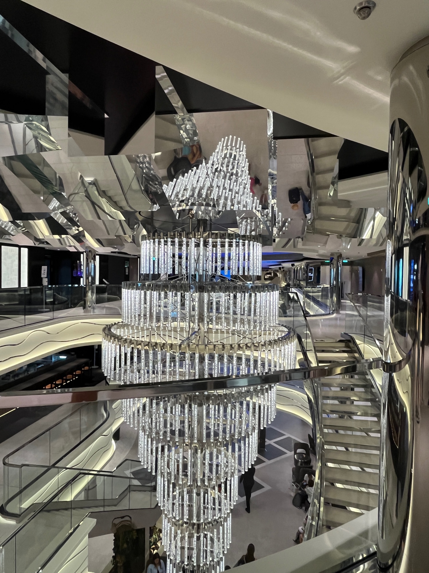 Overhead view of a modern shopping mall atrium with a large crystal chandelier and multiple floor levels