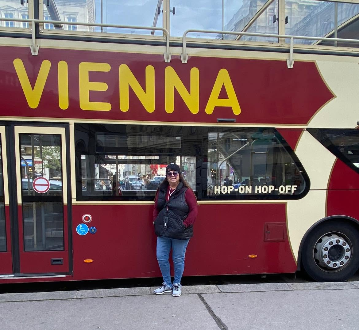 Kelly Carlton standing in front of a red and cream hop-on hop-off tour bus in Vienna
