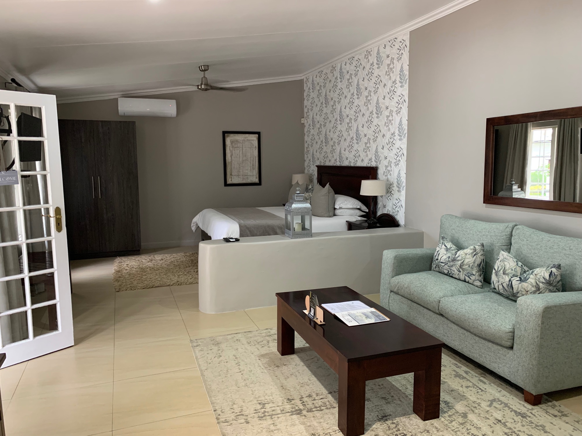 Modern bedroom suite with green sofa, dark wood bed, and neutral tones in a luxury accommodation