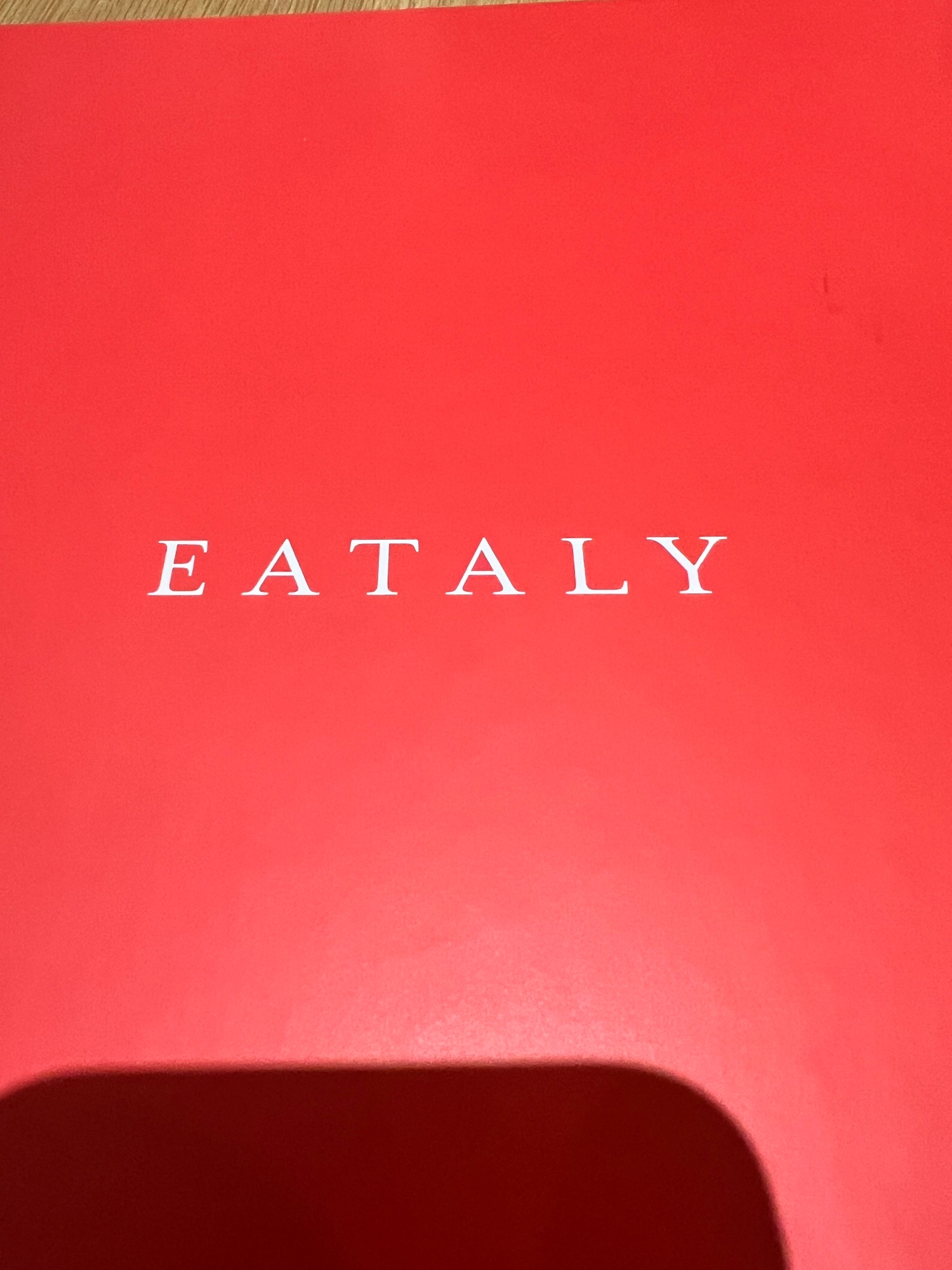 Eataly restaurant storefront with solid coral-red wall and white serif lettering
