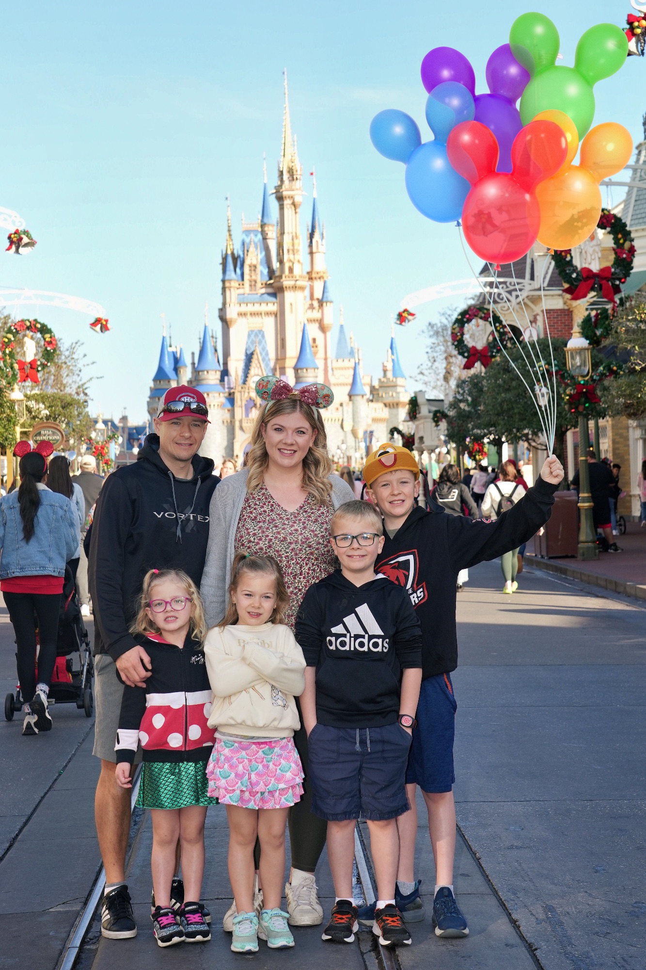 Family of six on a roller coaster ride with excited expressions and raised hands