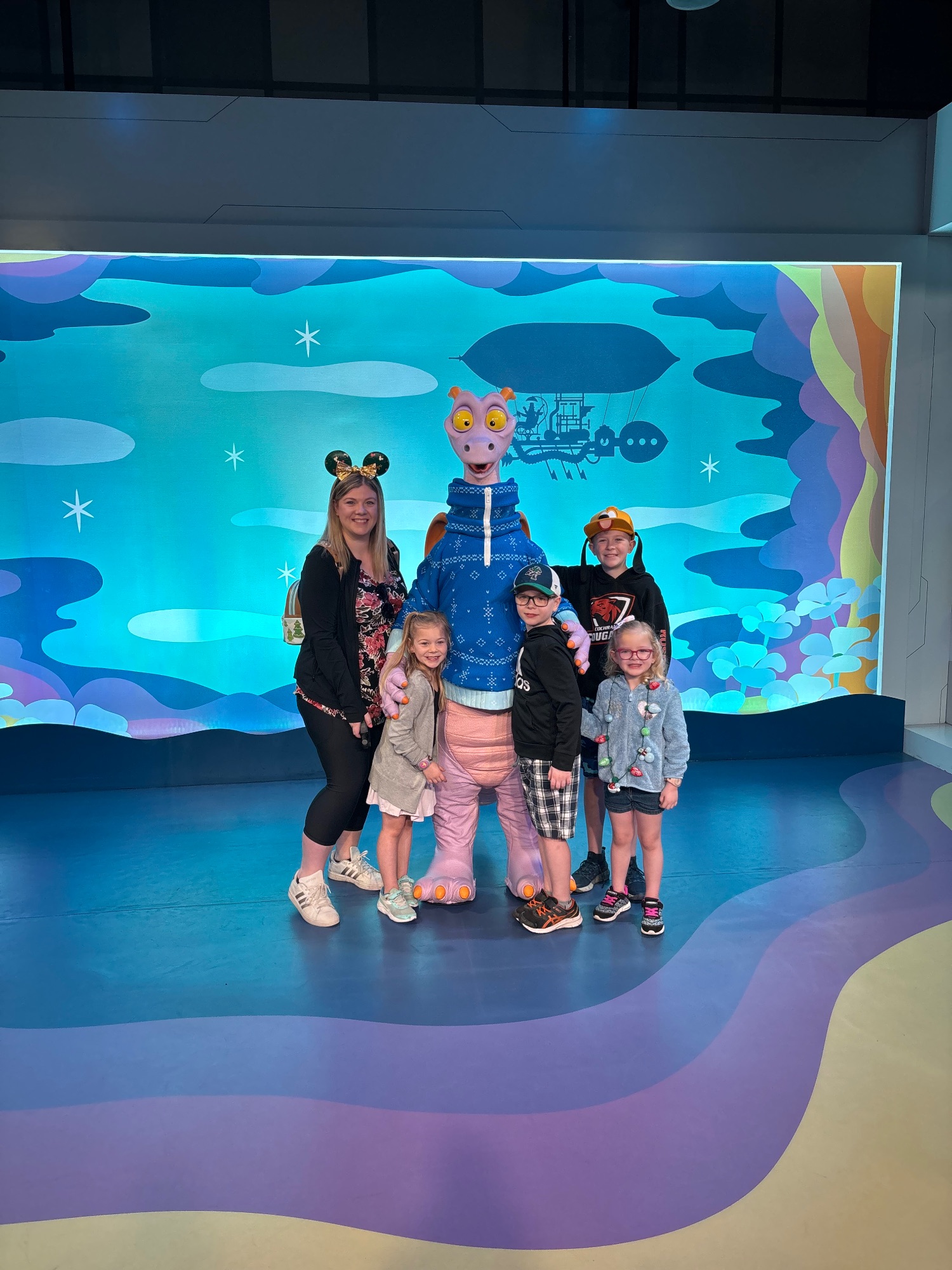 Family of six posing at a mini golf course with Spaceship Earth visible in the background at Epcot