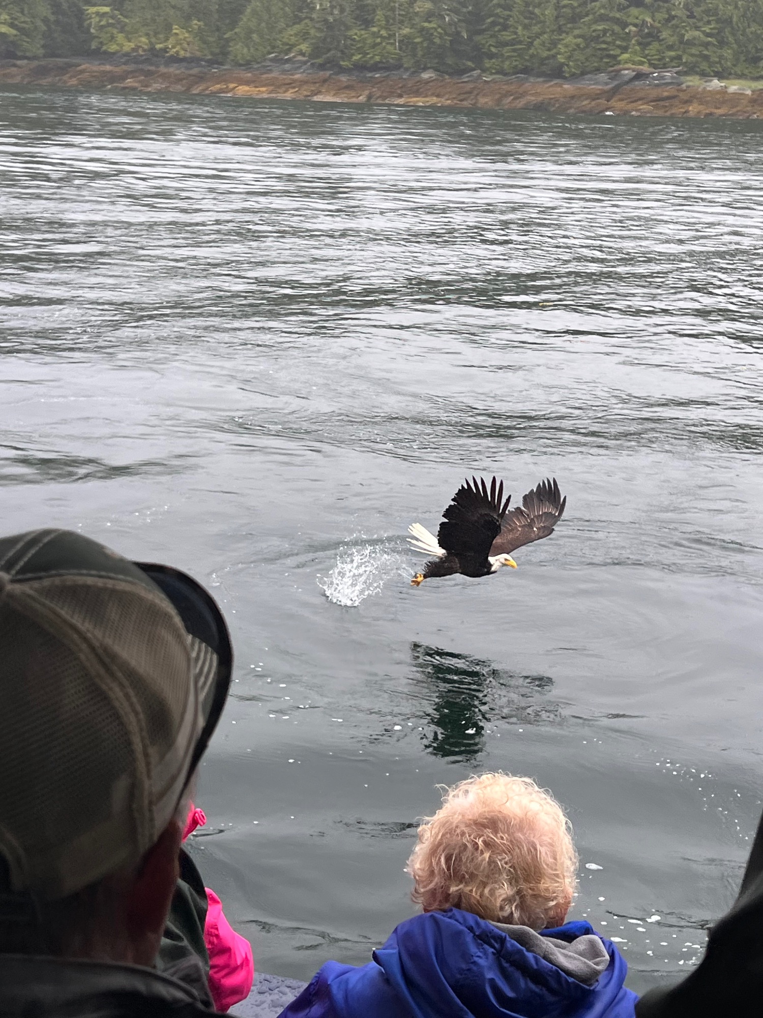 Woman holding halibut fish on charter boat with mountains and water visible