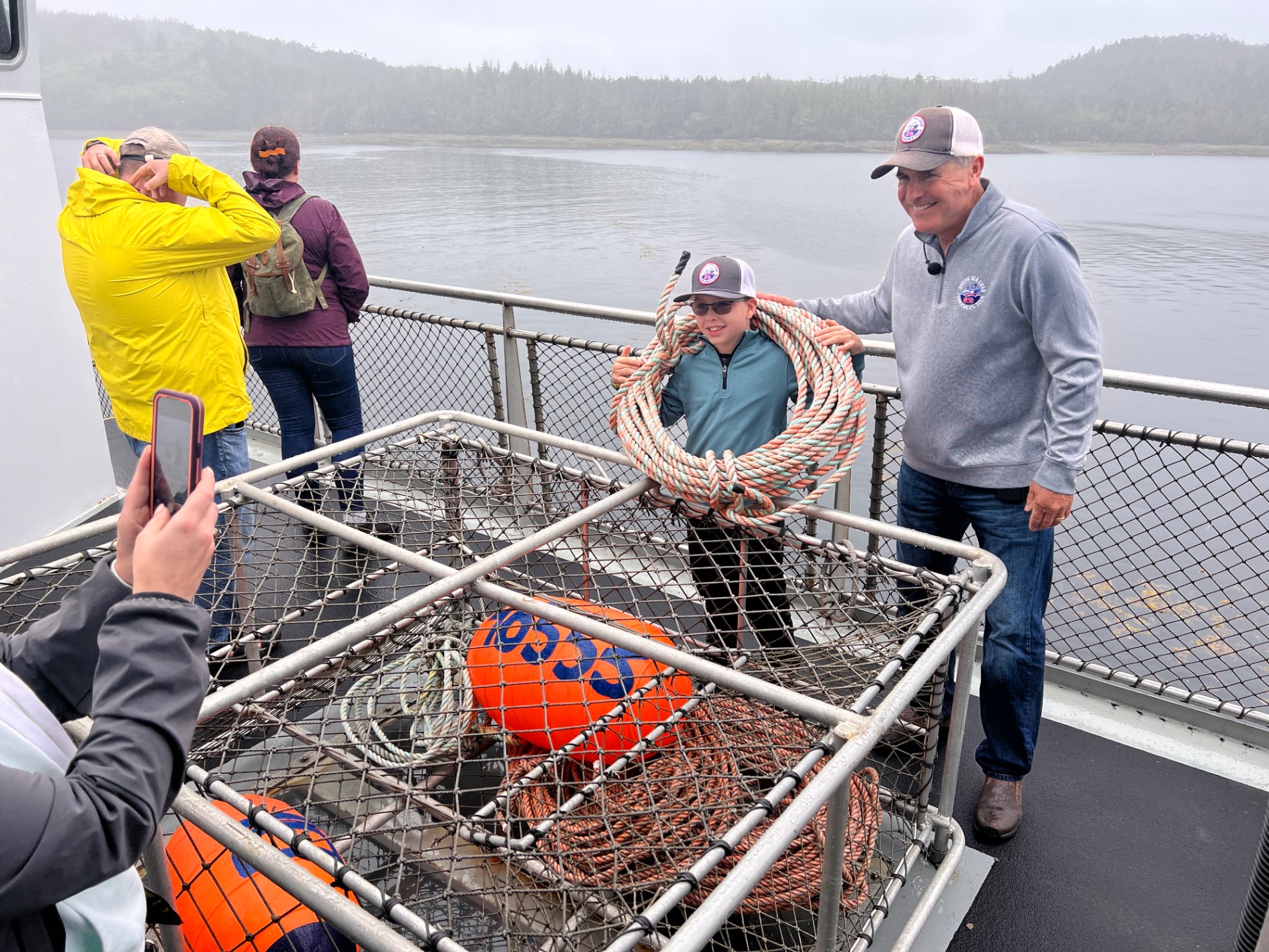 Man holding large catfish on boat with fishing rods mounted above