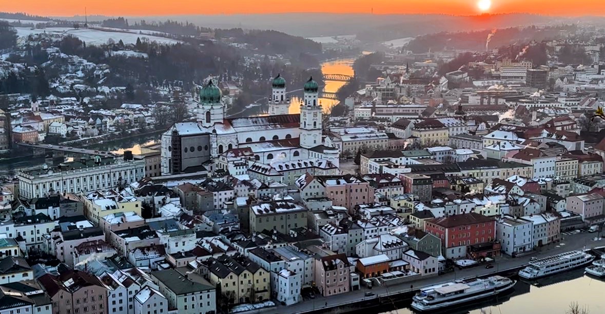 Aerial view of Passau, Germany at sunset with snow-covered roofs and illuminated churches