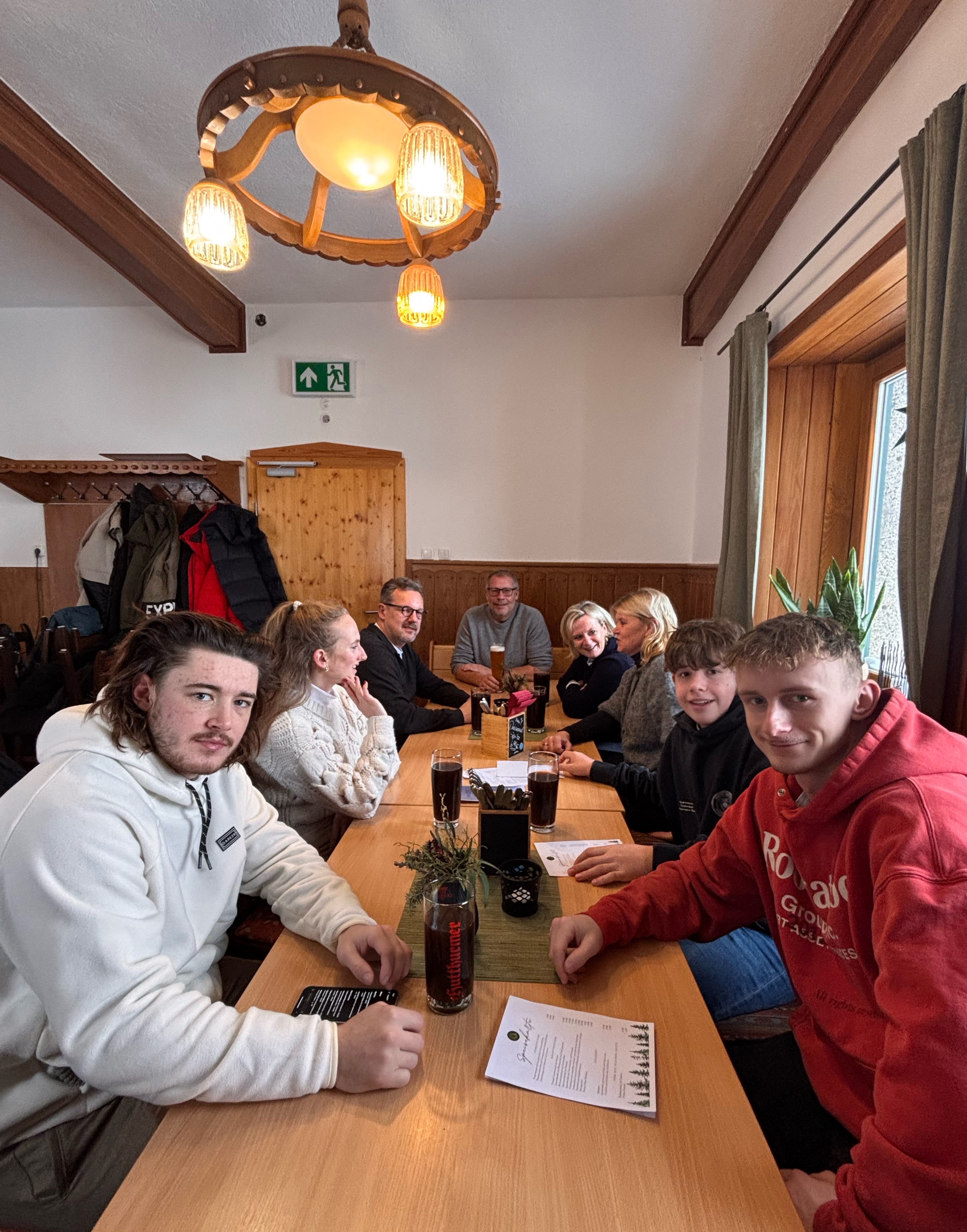 Group of people dining together at a wooden table in a rustic lodge interior