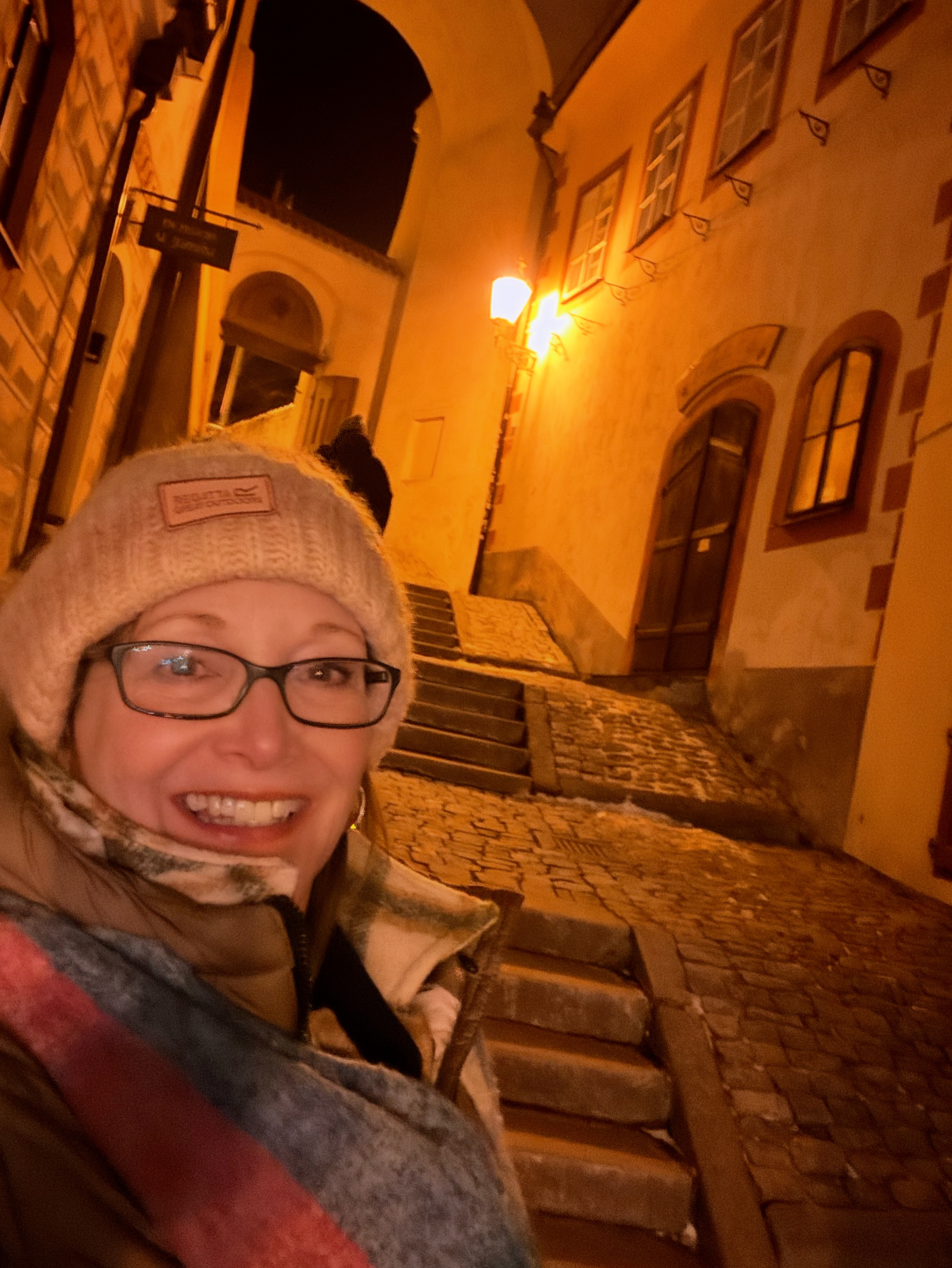 Woman smiling in a narrow cobblestone alley at night in a historic German town