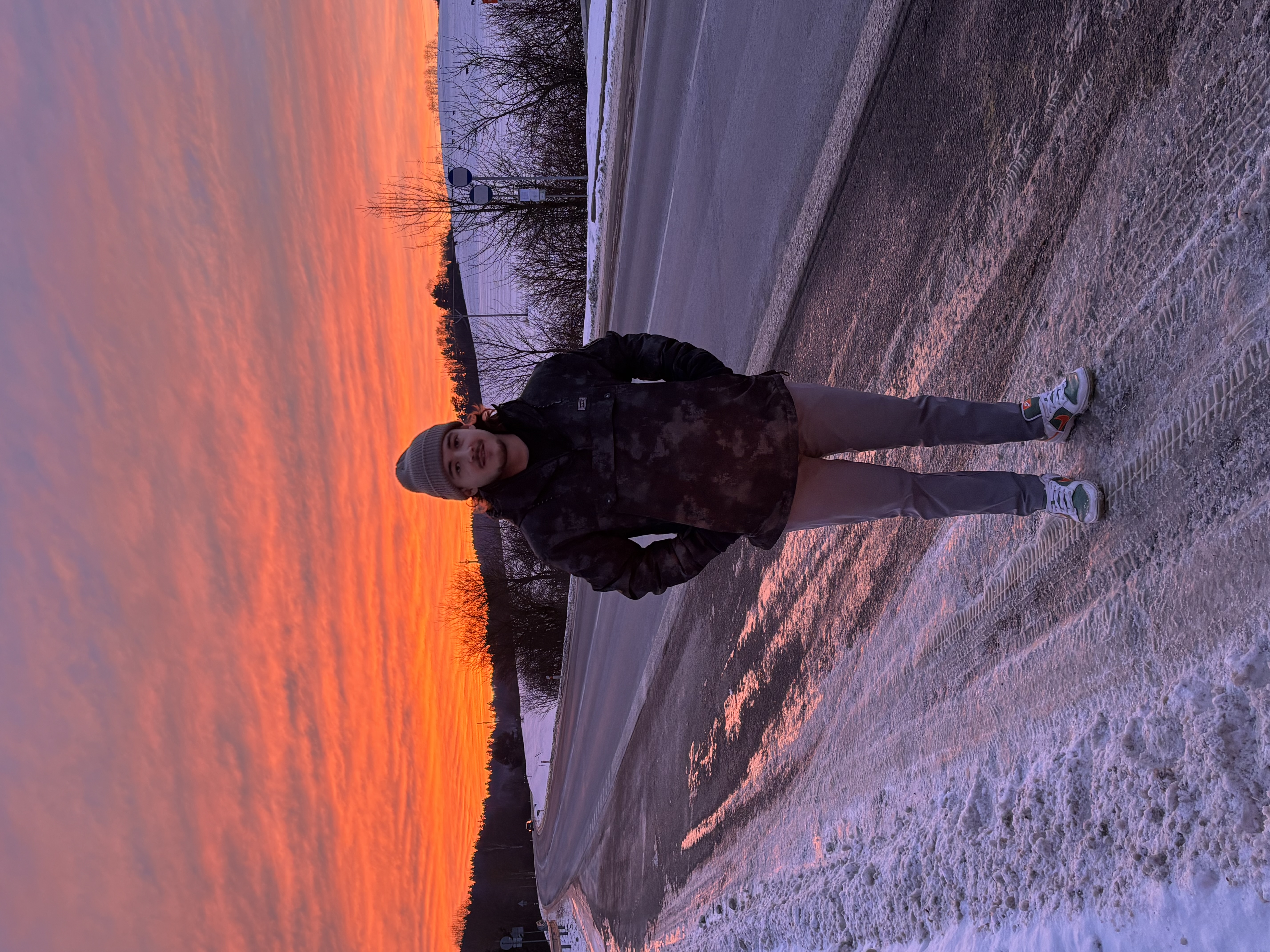 Man jogging on a snowy road at sunrise with forested hills in the background