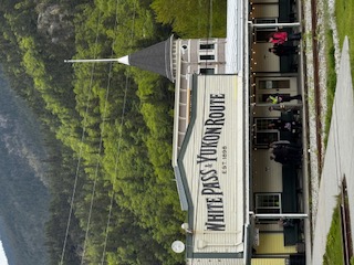 White Pass and Yukon Route railway station building with peaked roof nestled among evergreen trees in a mountain valley