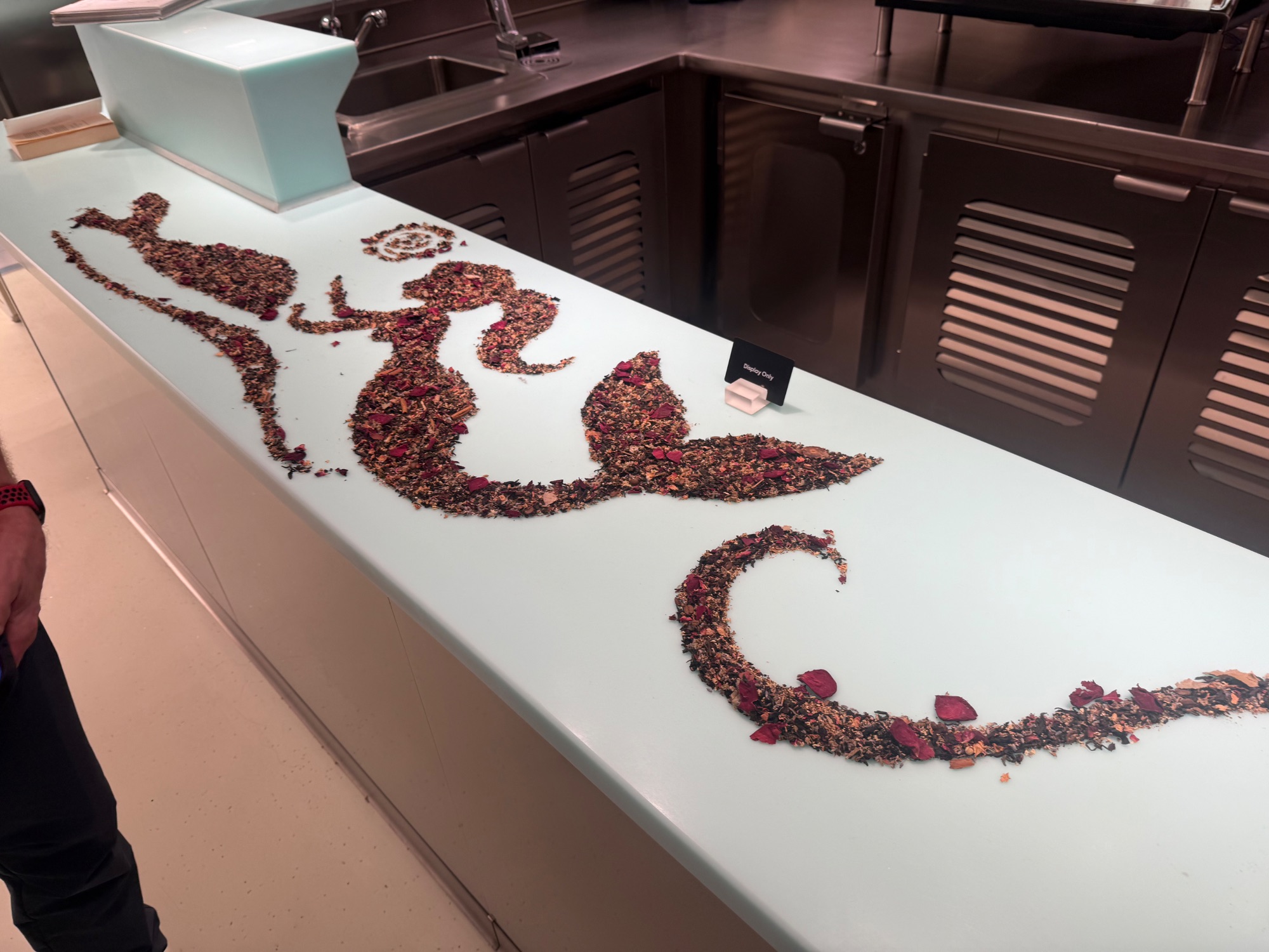 Modern ship dining venue with bar seating, glass counter, and staff preparing drinks