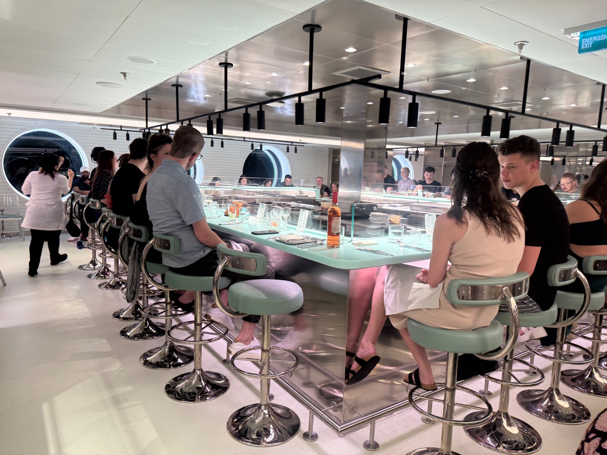 Woman in black dress at ship's modern bar with illuminated circular wall fixtures