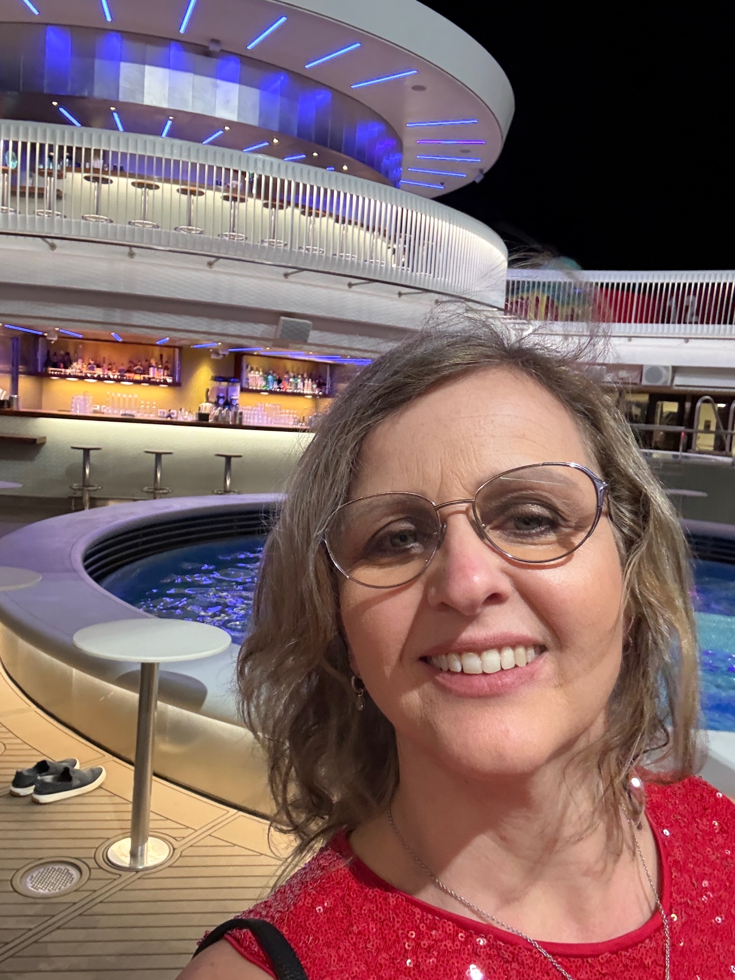 Woman in glasses smiling at modern ship bar with blue lighting and curved architecture