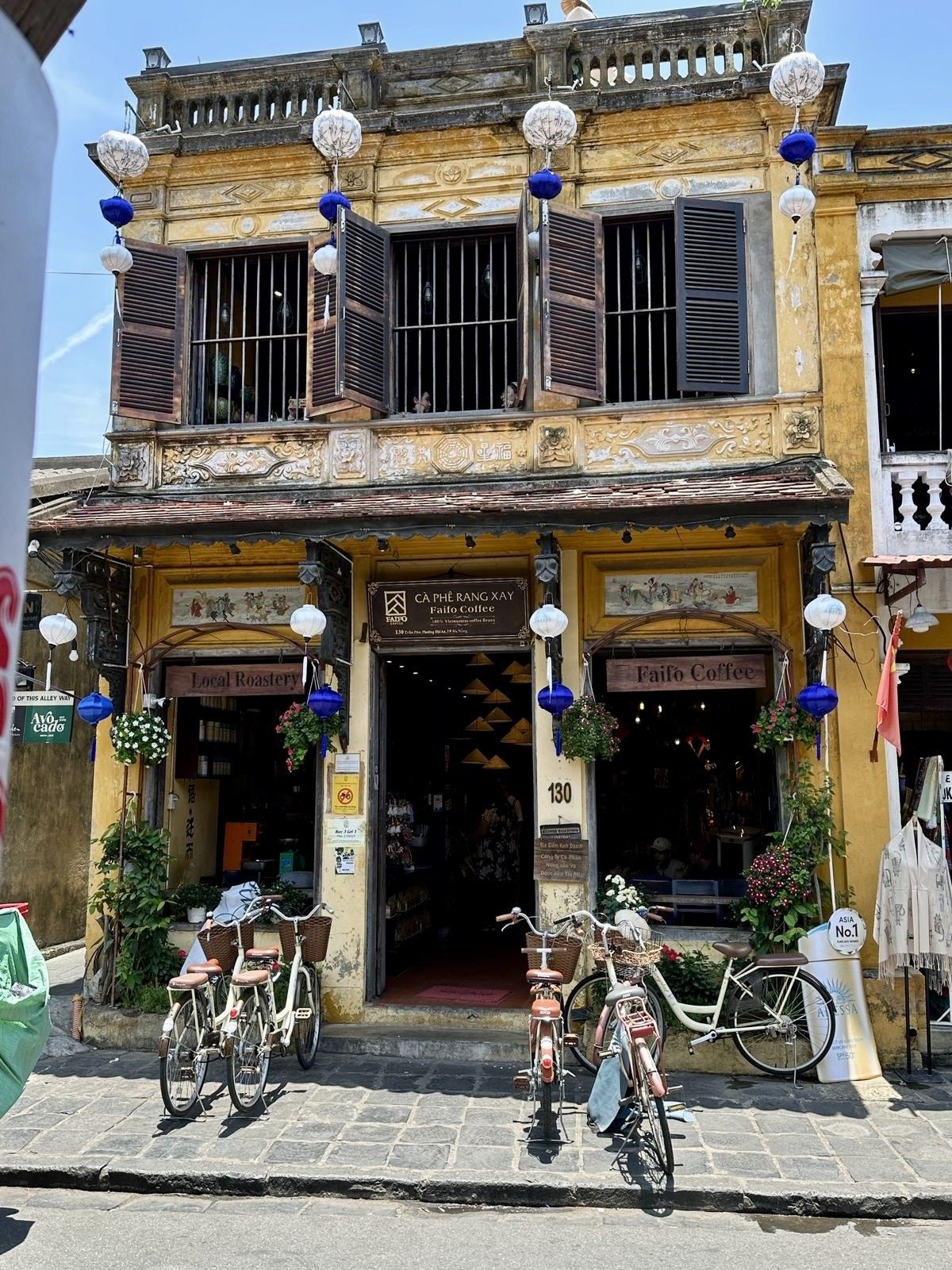 Rooftop coffee bar overlooking Hoi An with ivy-covered yellow building and street below