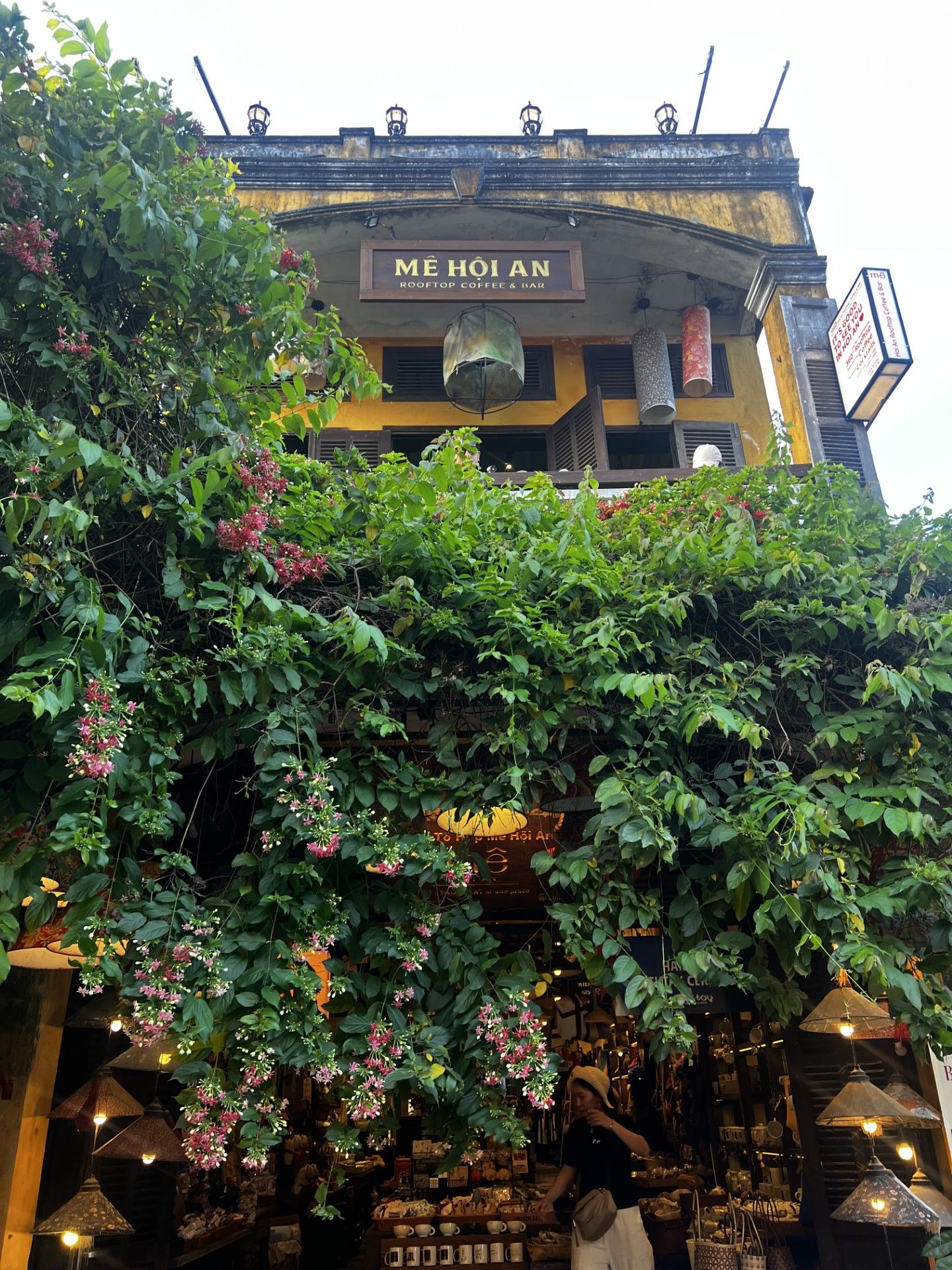 White colonial-style hotel building with curved balconies and palm trees lining the entrance