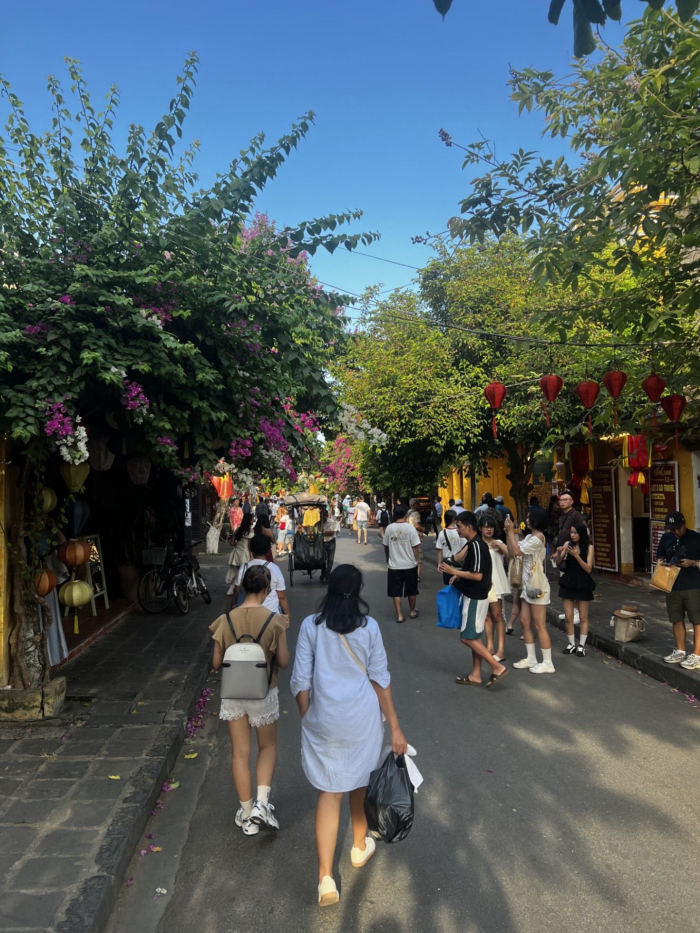 Hoi An Ancient Town pedestrian street with yellow buildings, hanging lanterns, and crowds of visitors