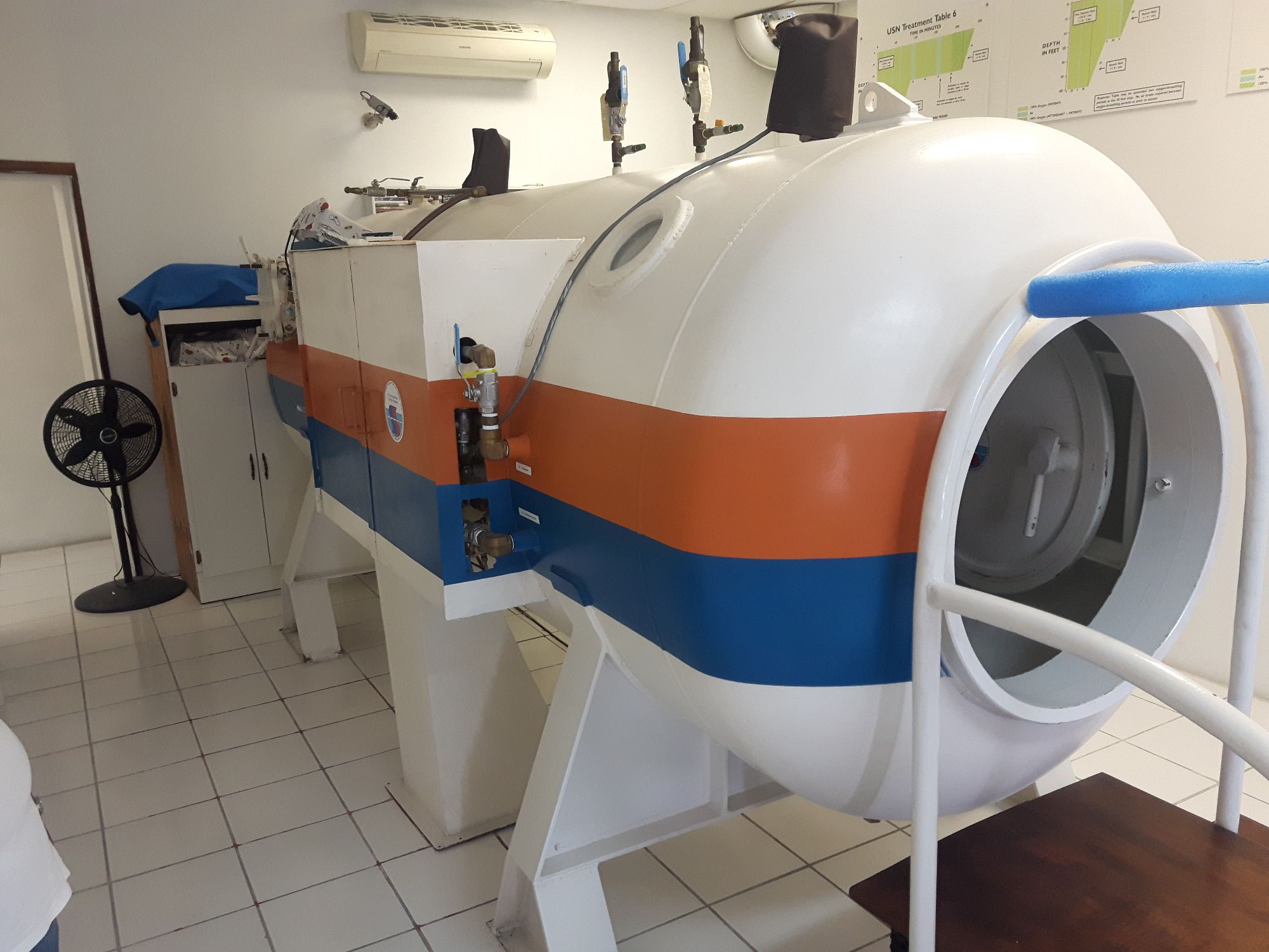Hyperbaric oxygen chamber with blue and orange stripes in a medical facility room