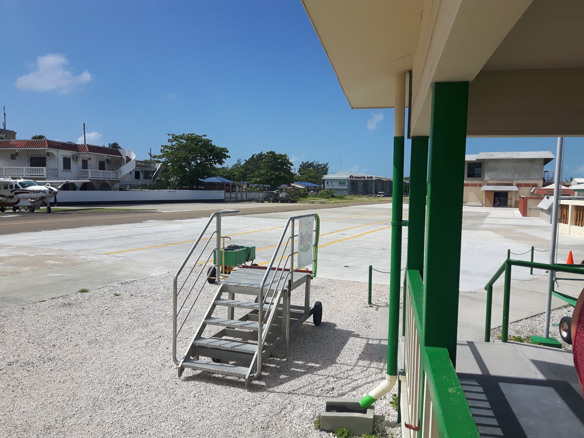 Concrete airstrip with metal stairs and green support structures at a small airport in Belize