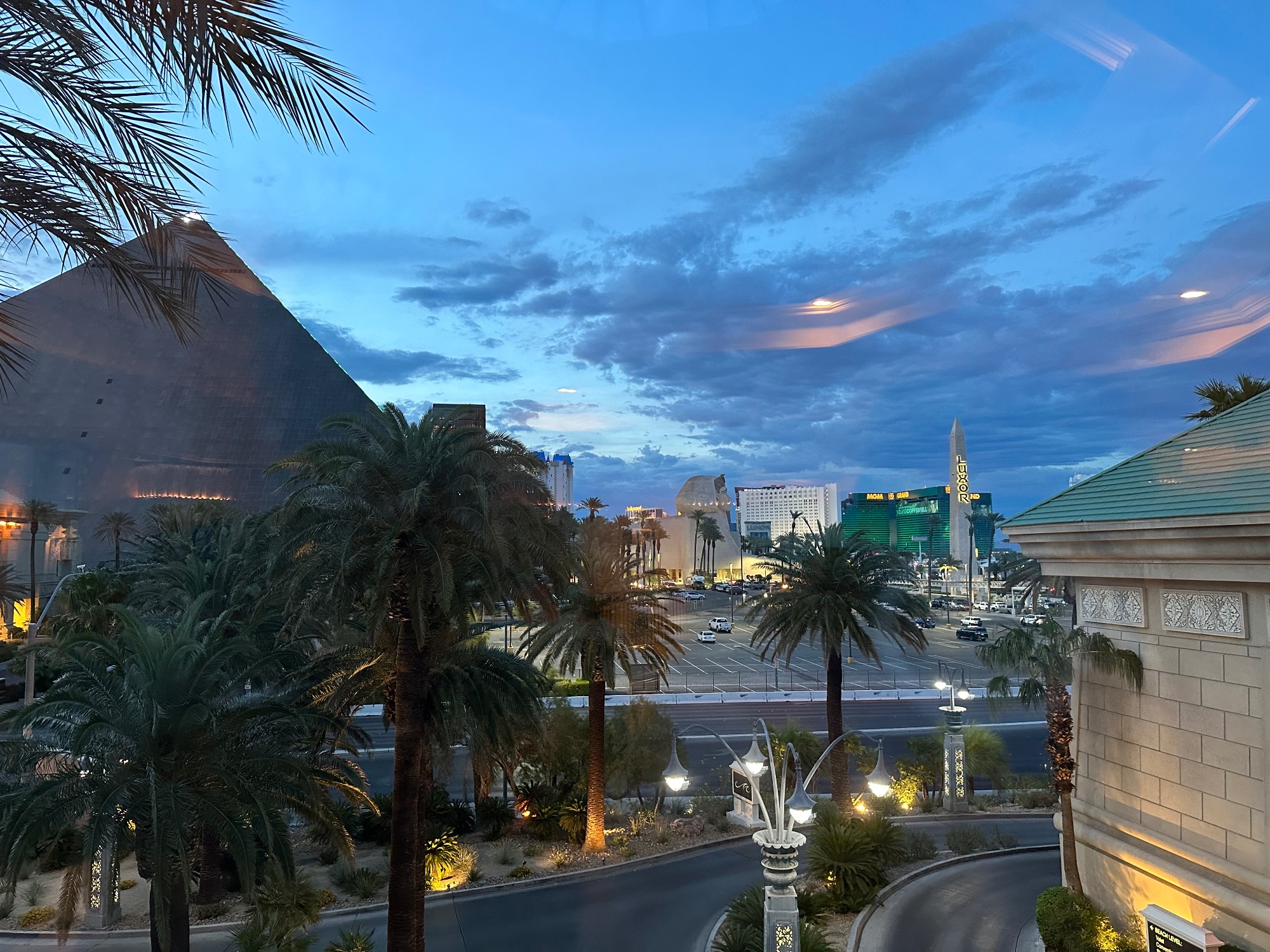 Las Vegas Strip view at dusk showing palm trees, illuminated casino hotels, and Egyptian-themed sphinx statue