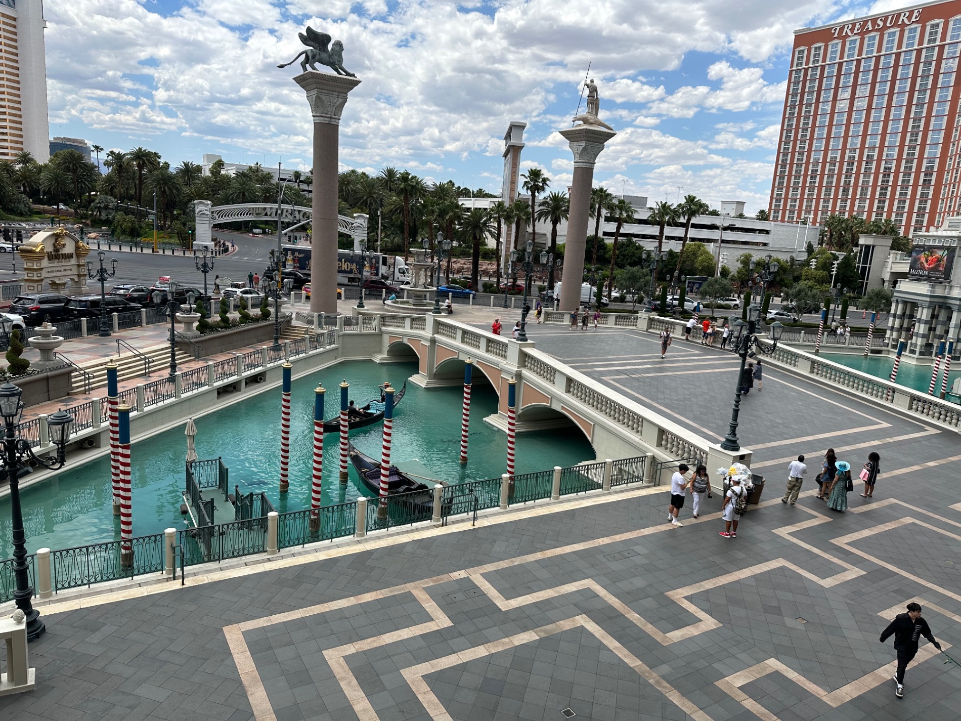 Bellagio Fountains plaza with turquoise water features, ornate columns, and Las Vegas cityscape at daytime