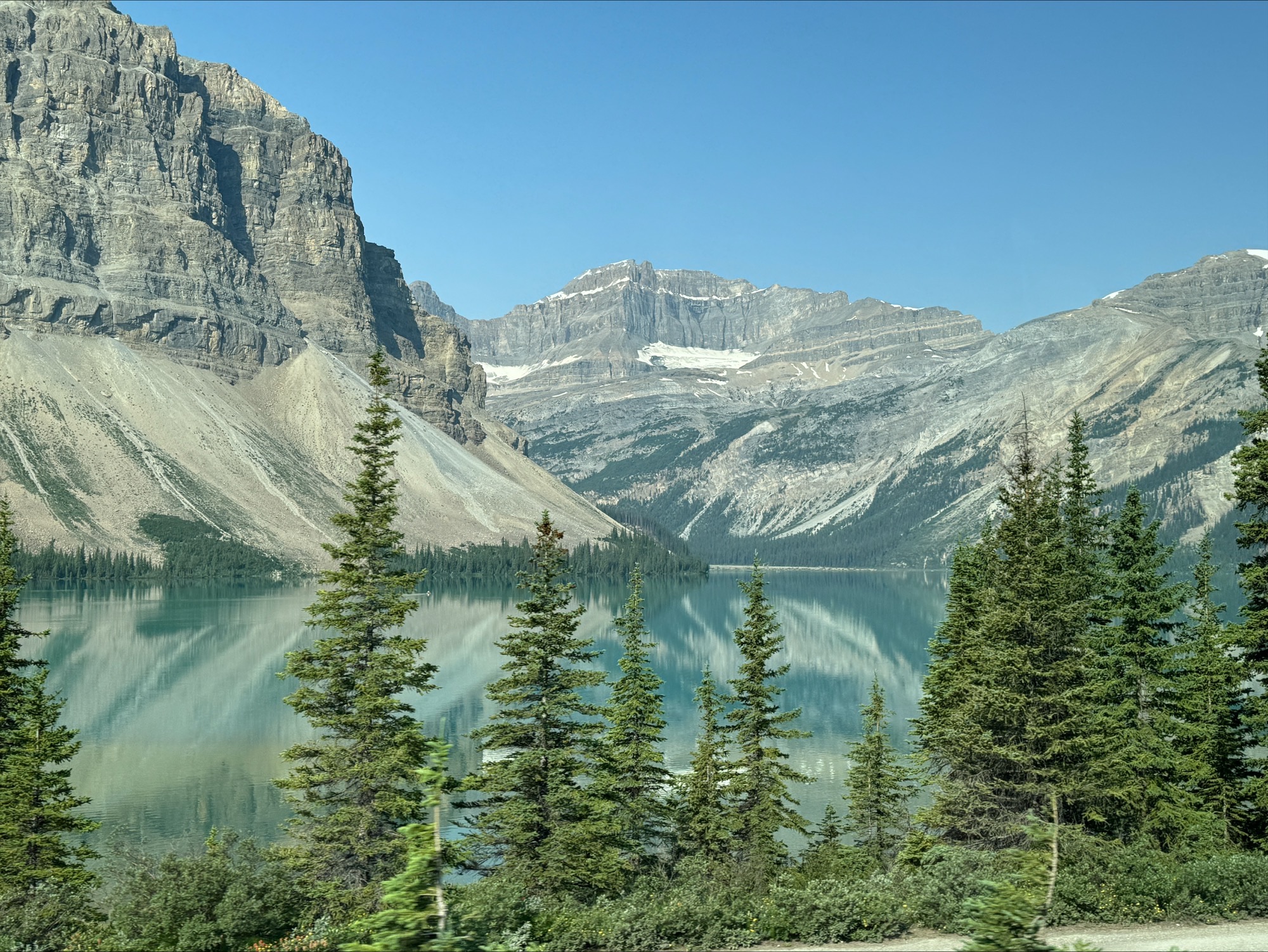 Turquoise glacial lake surrounded by steep rocky mountains and coniferous forest