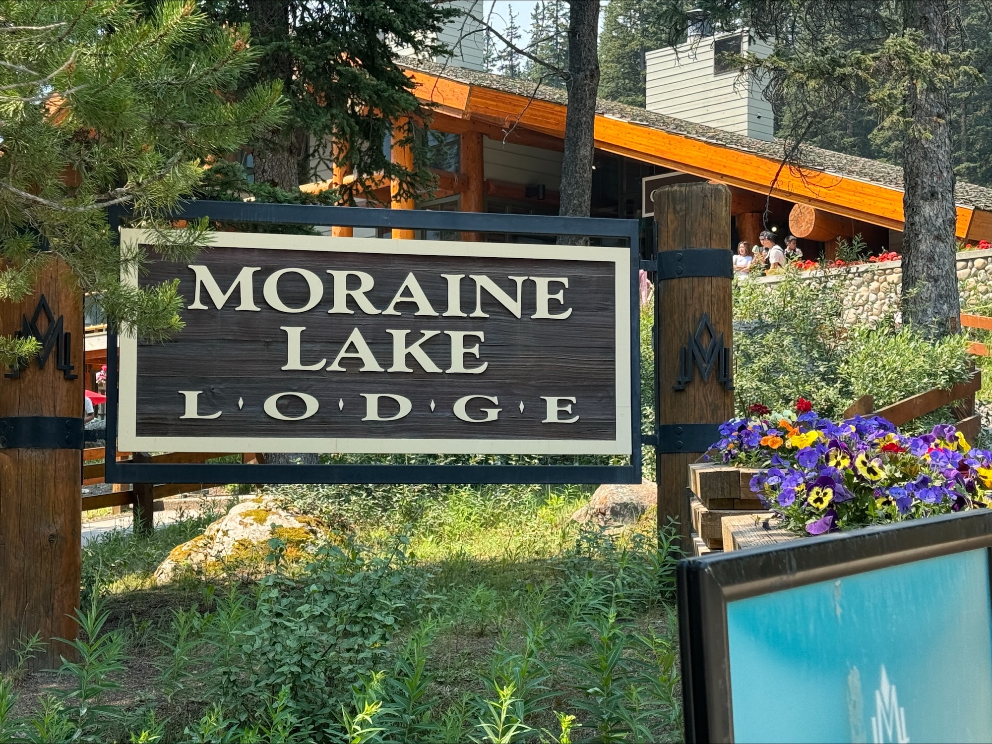 Moraine Lake Lodge sign with colorful flowers in front of a wooden lodge building