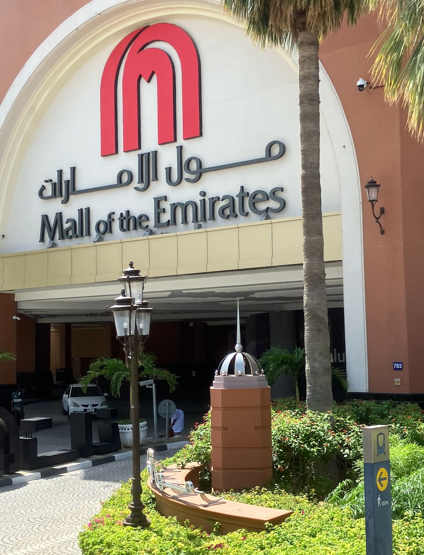 Mall of the Emirates entrance sign with palm trees and landscaping in front of the building