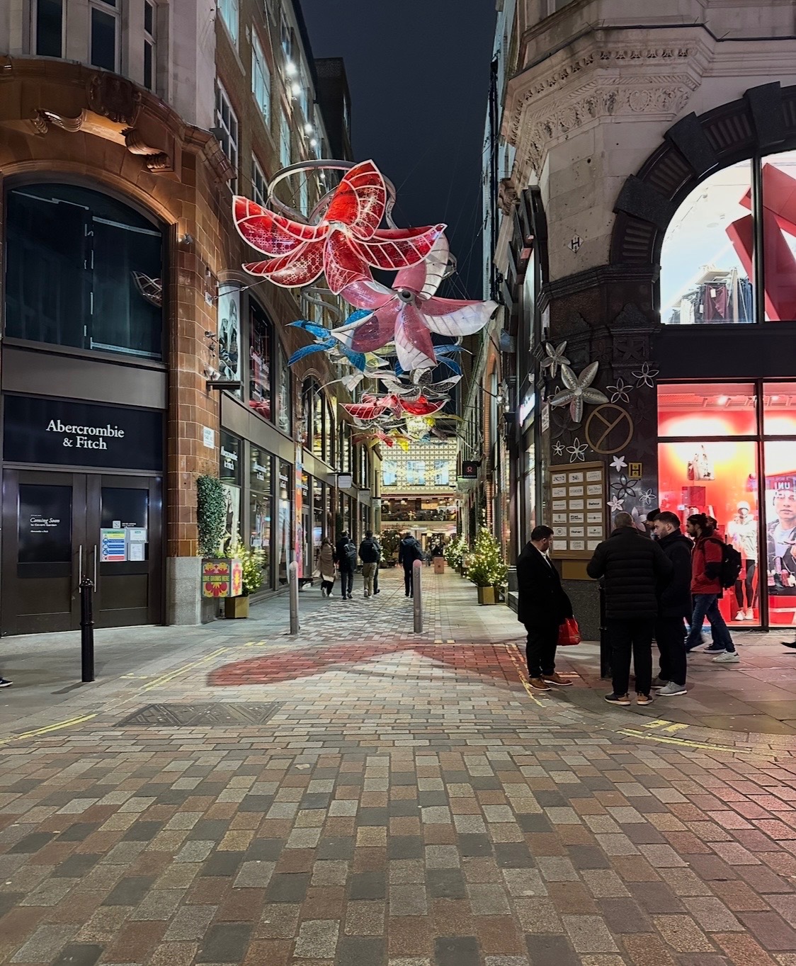Regent Street at night with elaborate golden light installations spanning across the street and illuminated storefronts