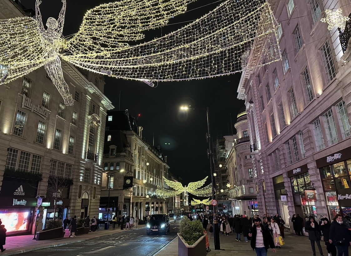 Piccadilly Circus area with tall illuminated Christmas tree covered in thousands of white and colored lights at night