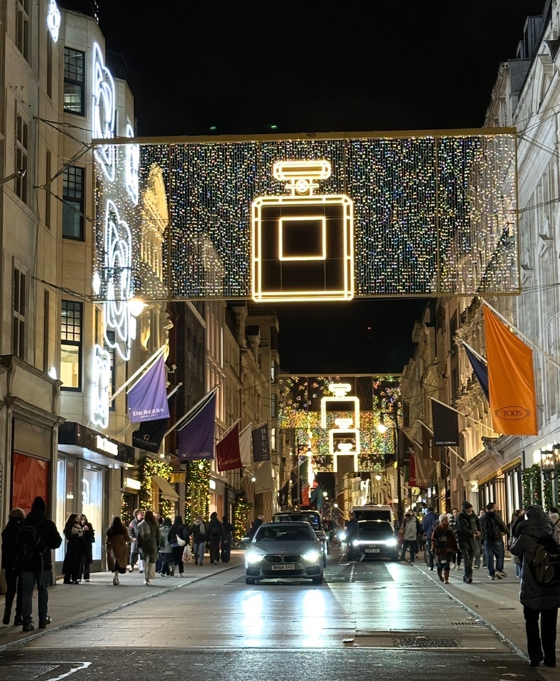 Bond Street at night with elaborate golden light installations creating geometric patterns overhead and holiday decorations on storefronts