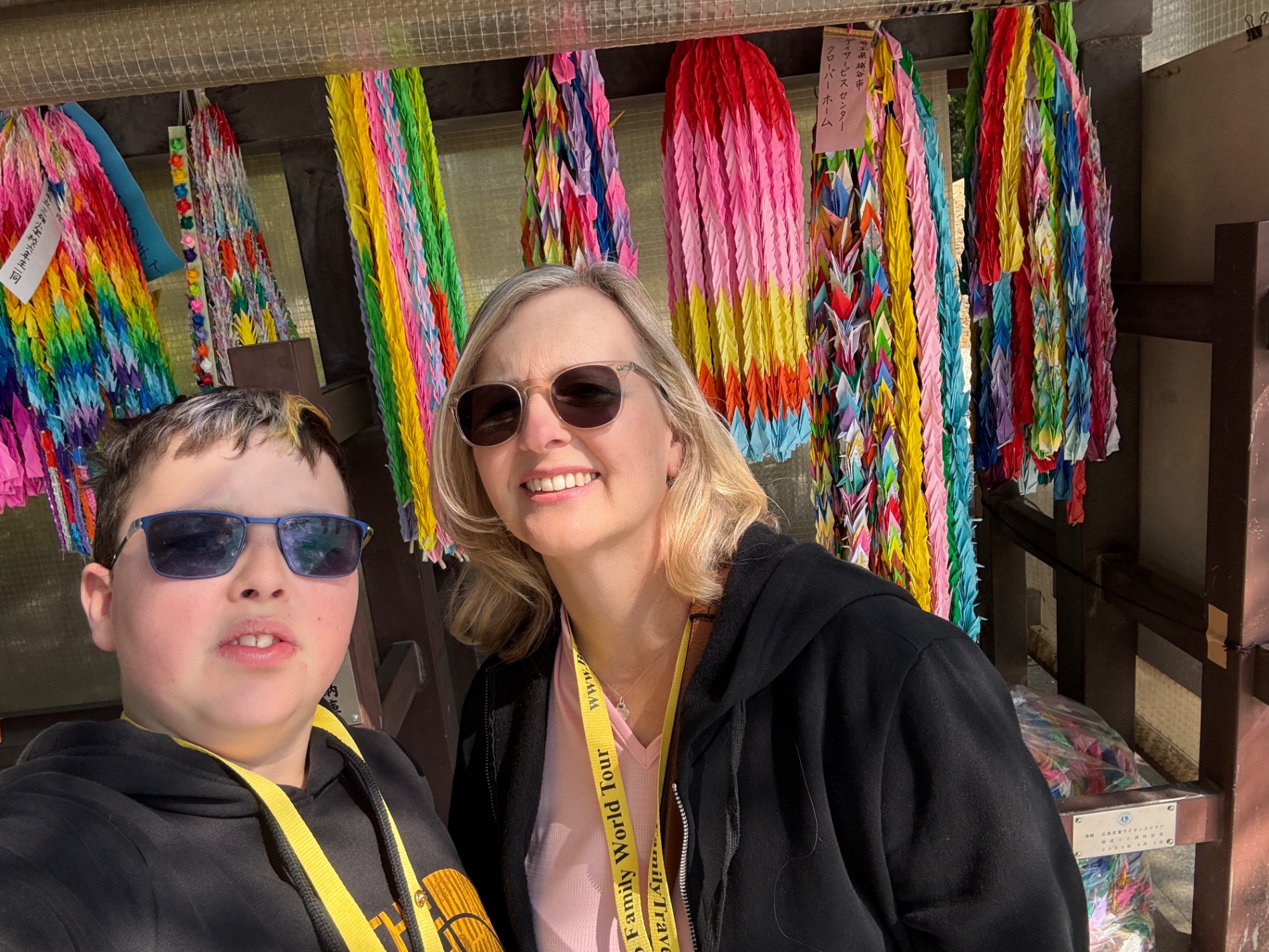Marcia White and a young person posing in front of colorful hanging paper decorations at a Japanese temple or shrine