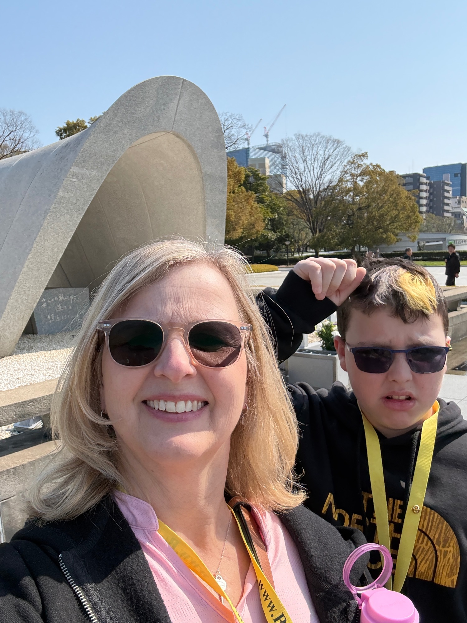Marcia White and a young person at a modern public plaza with a large curved concrete sculpture and city buildings