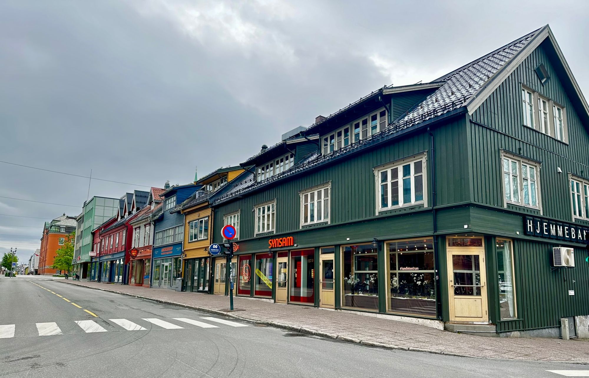 Colorful traditional Nordic buildings with green and red facades lining a pedestrian street