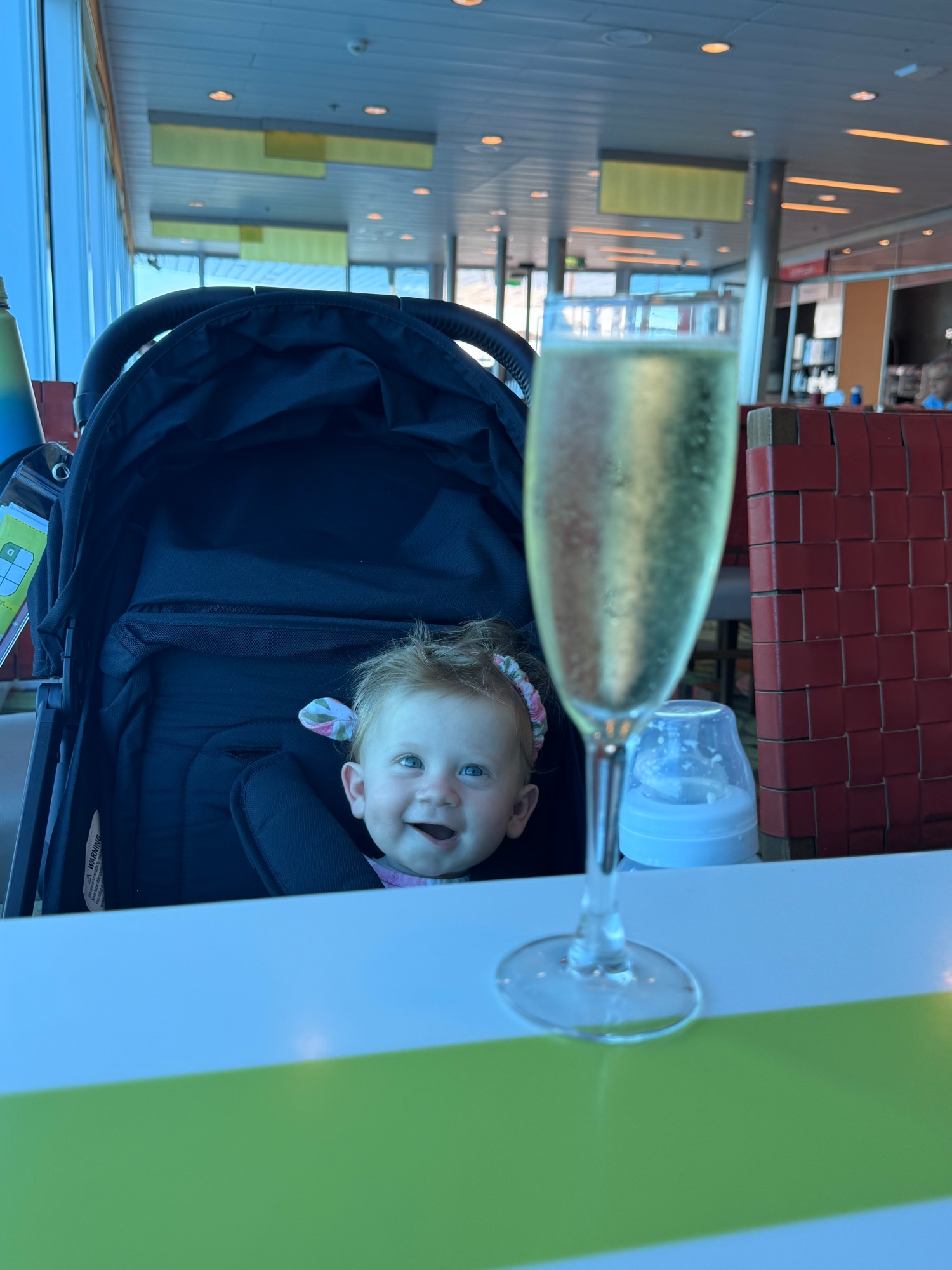 Man holding a baby in a cruise ship dining room with ocean views through windows