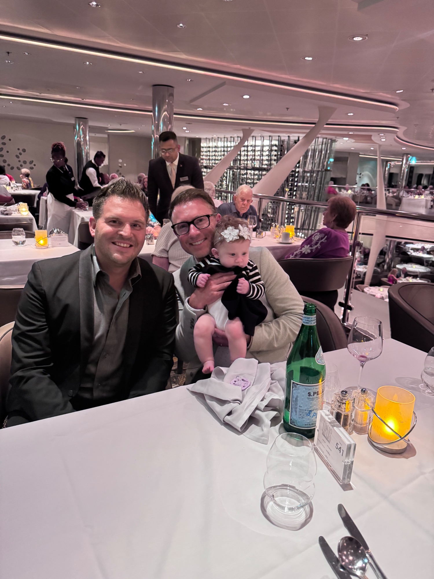 Man holding a baby in a casual dining area on a cruise ship with ocean backdrop