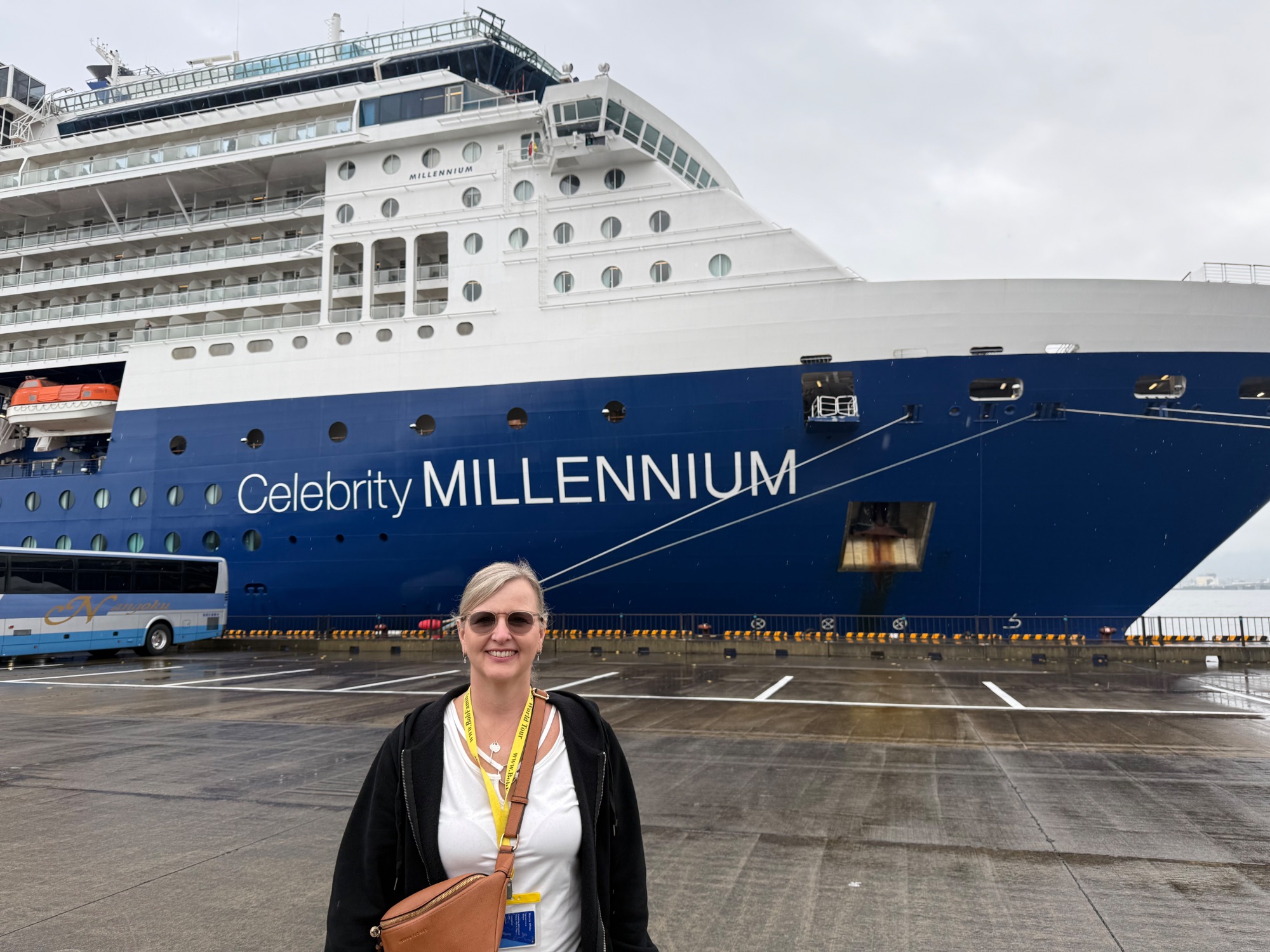 Woman standing in front of the Celebrity Millennium cruise ship docked at a Japanese port