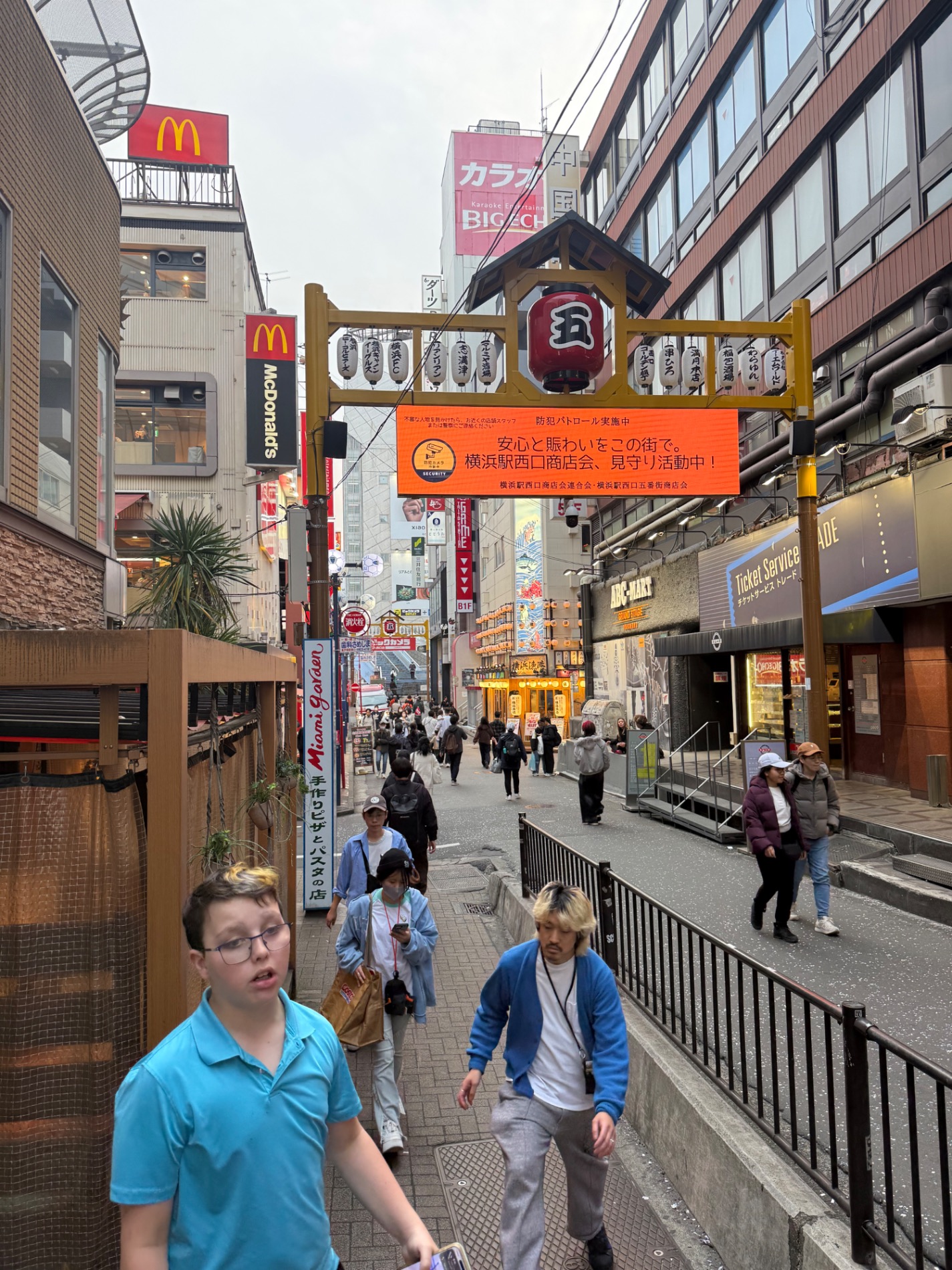 Boy walking through a covered shopping arcade with McDonald's and Japanese restaurant signs visible