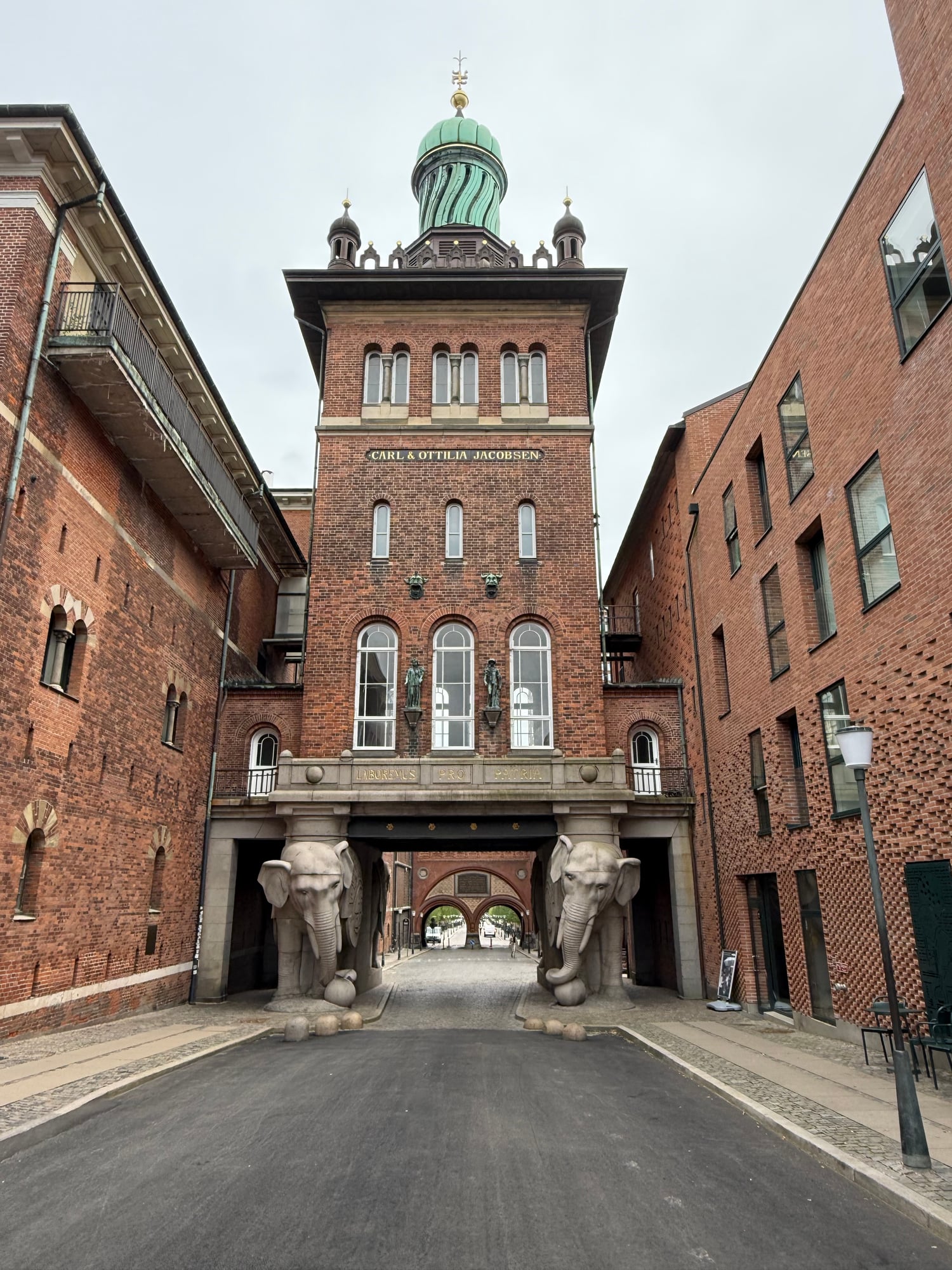 A brick building with a green copper dome and tower labeled Carl & Ottilia Jacobsen, flanked by brick structures