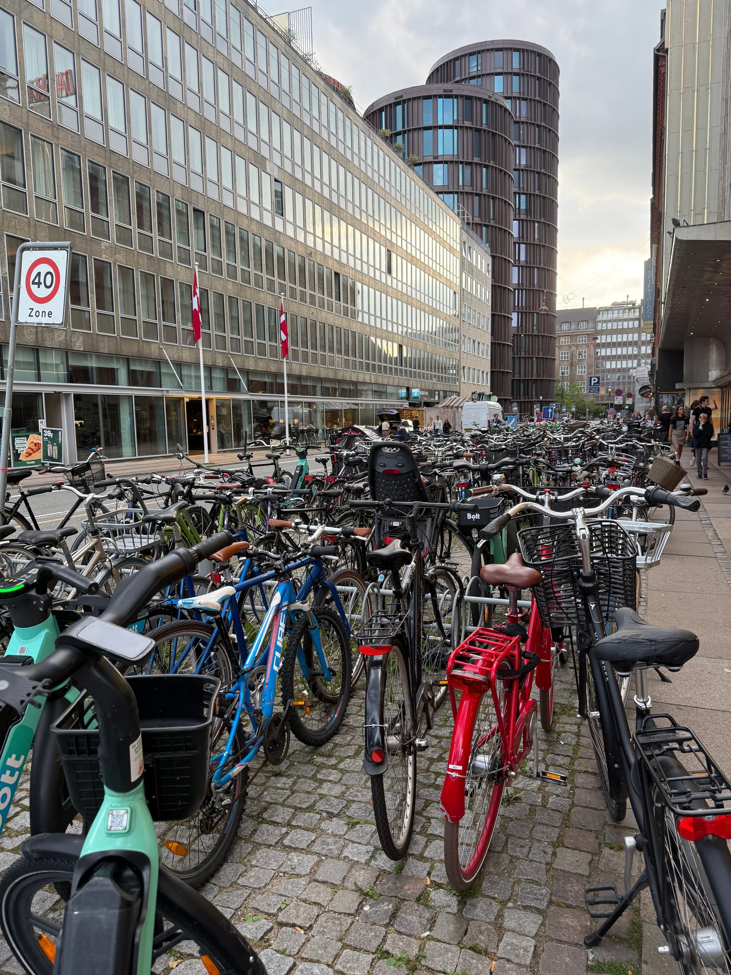 Hundreds of bicycles parked densely in an urban plaza with modern buildings and a 40 km/h zone sign