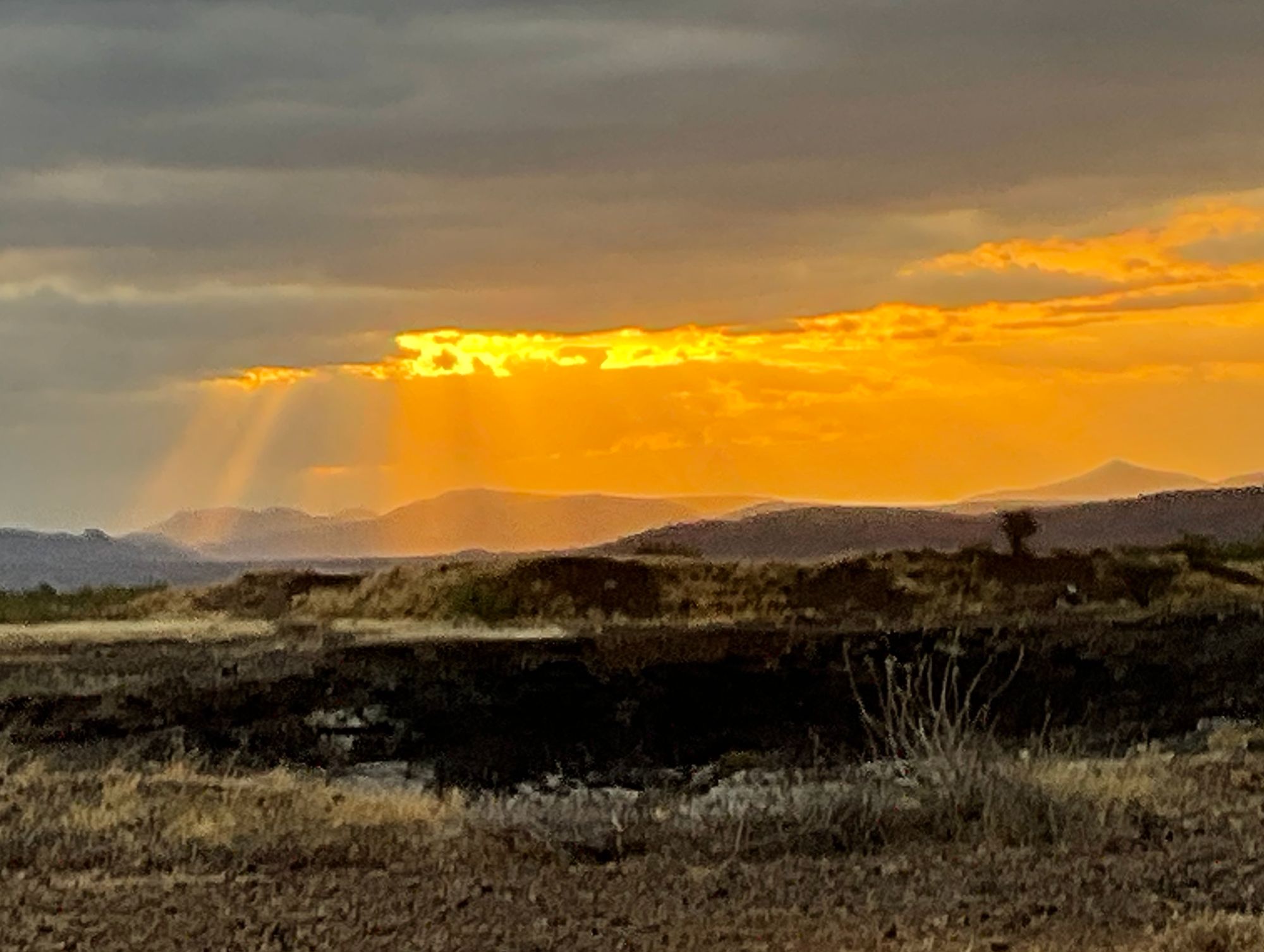 Golden sunset over Kenya landscape with dramatic clouds and sun rays breaking through