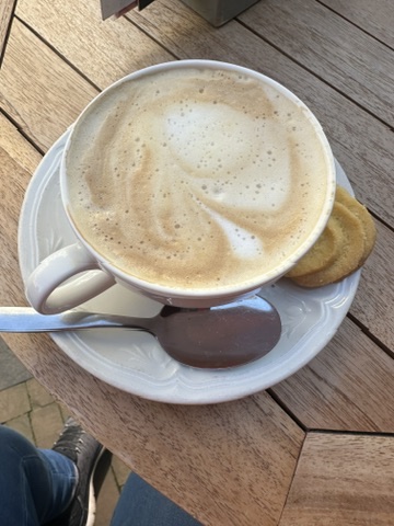 Cappuccino with latte art and chocolate biscuit on wooden table at a café