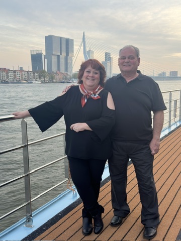 Alison Rieger and companion posing on a river cruise ship deck with Rotterdam skyline in background