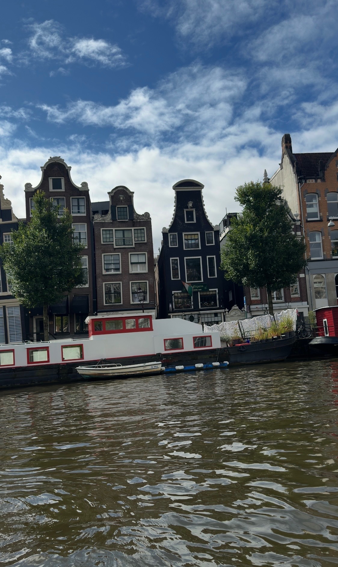 Historic Dutch canal houses with characteristic gabled roofs reflected in calm water with a moored boat