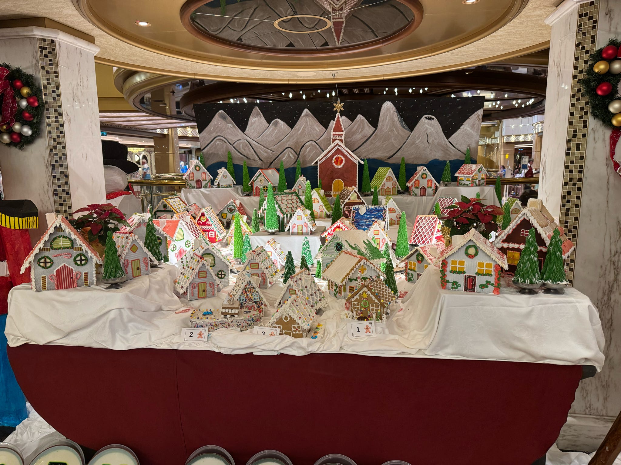 An elaborate gingerbread house competition display aboard a decorated cruise ship at Christmas.